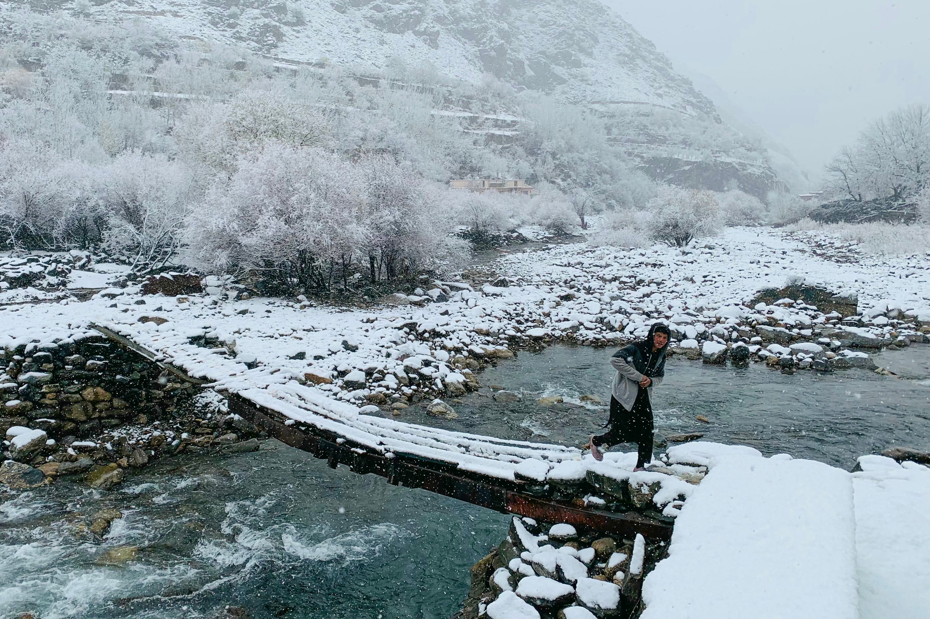 A boy walks across a footbridge during the first snowfall in Dara district of Panjshir province, Afghanistan, on 2 December