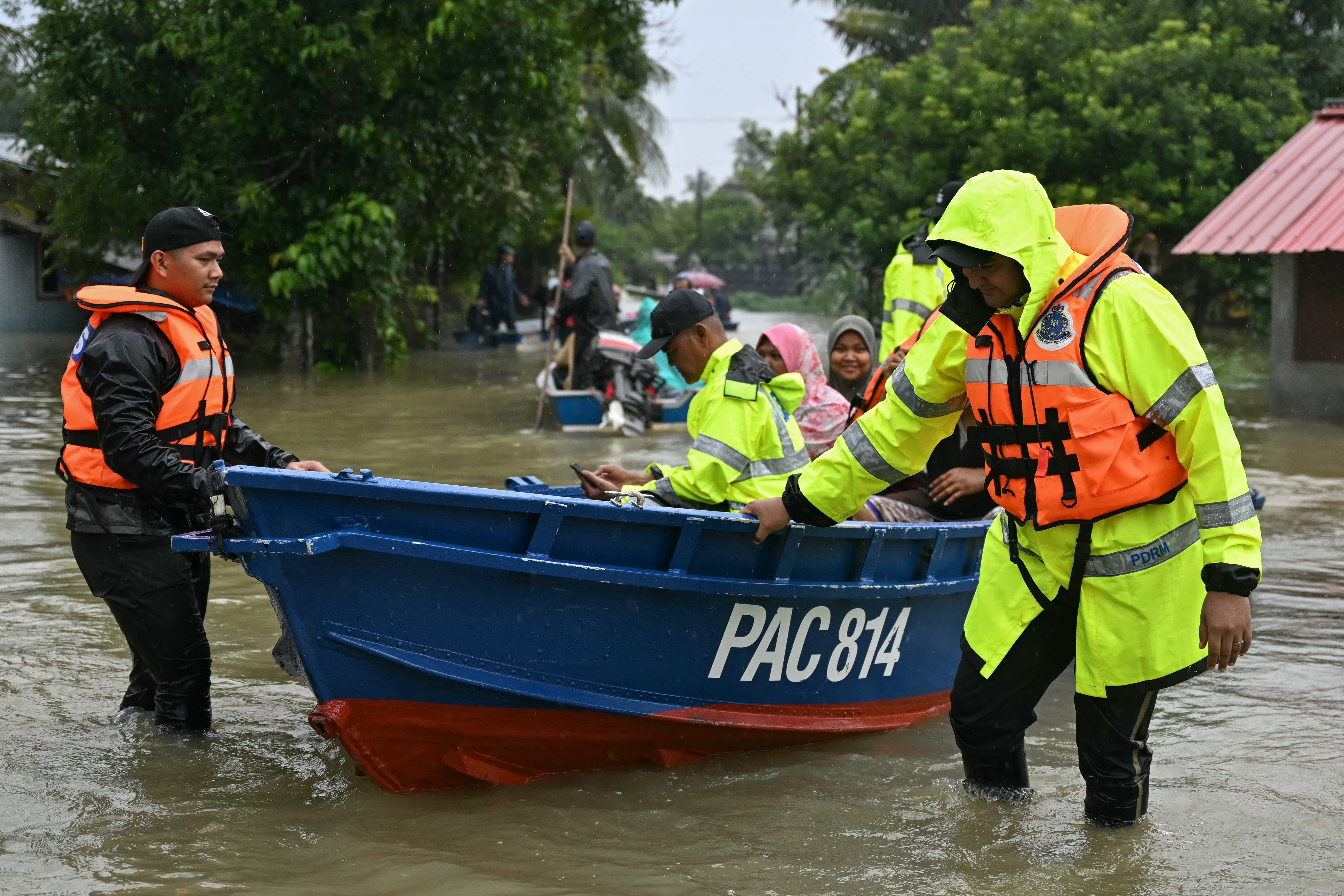 Royal Malaysia Police transport residents on a boat through floodwaters after days of heavy rain in Tumpat