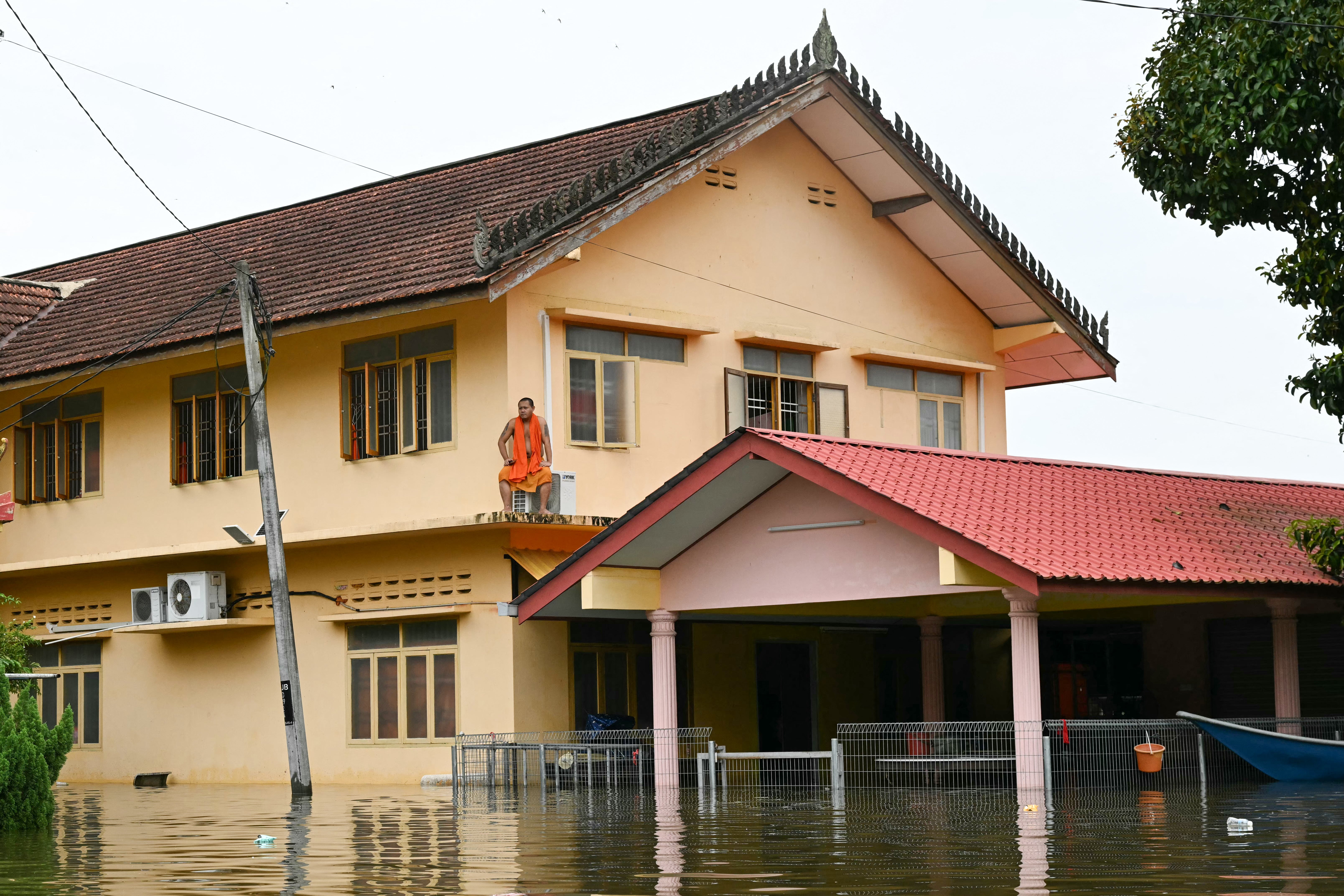 A Buddhist monk sits on the second floor of a building surrounded by floodwaters in Tumpat, Malaysia