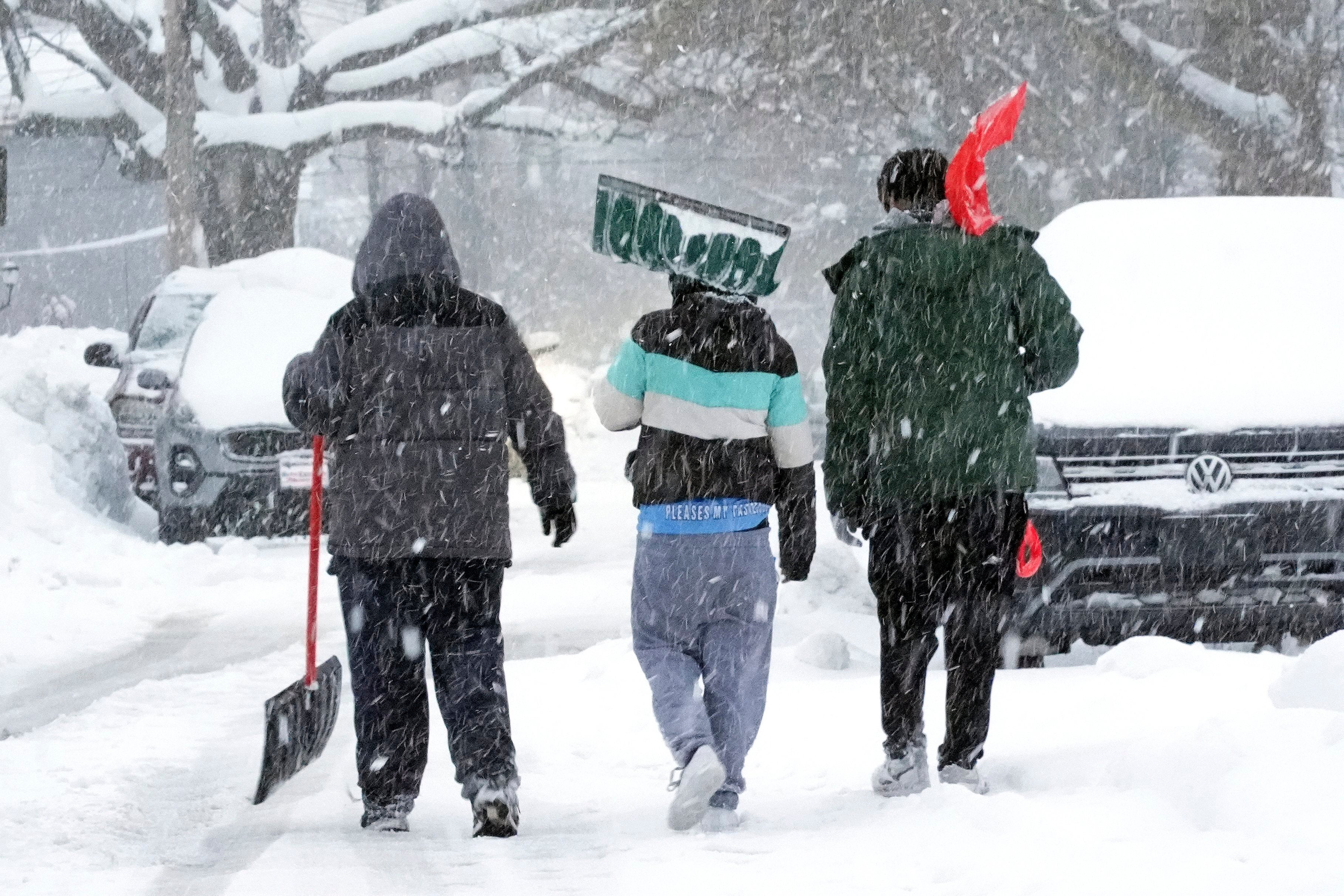 Boys walk down a snow-covered side street in Erie, Pennsylvia, on Monday. More snow is forecast this week across the U.S.