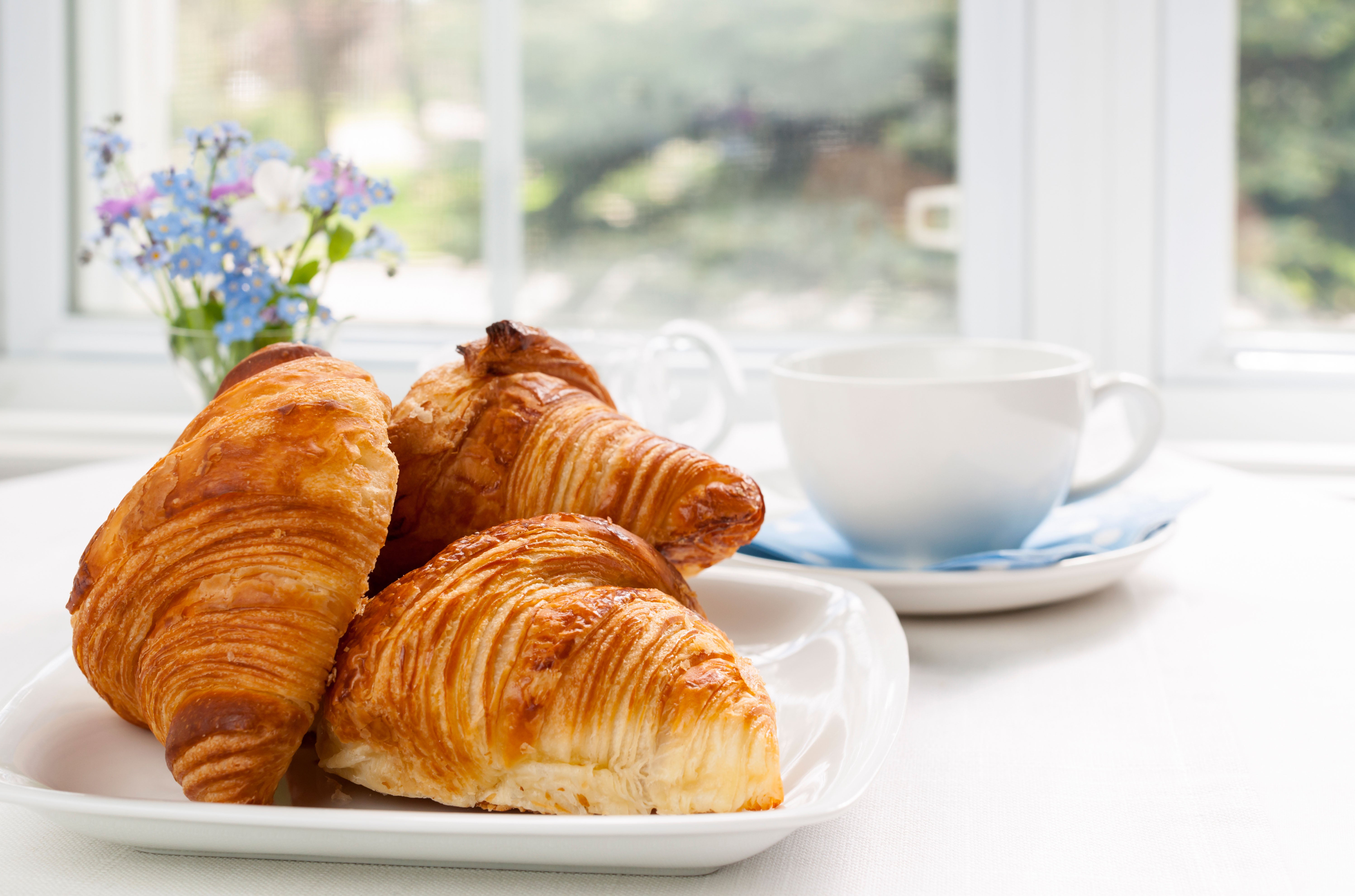 Three fresh baked croissants on plate for breakfast