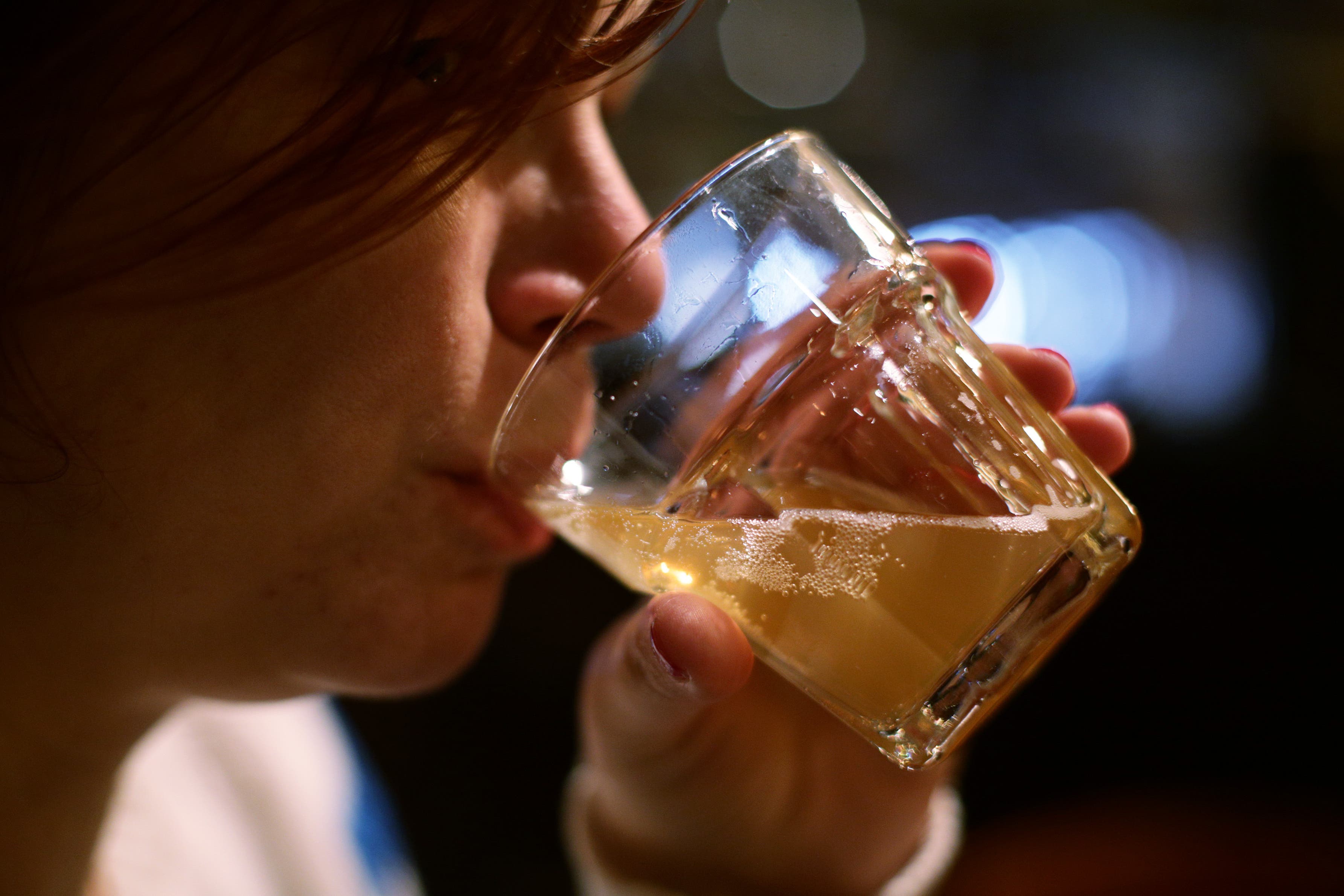 A woman drinking a glass of beer in a pub in London (Yui Mok/PA)