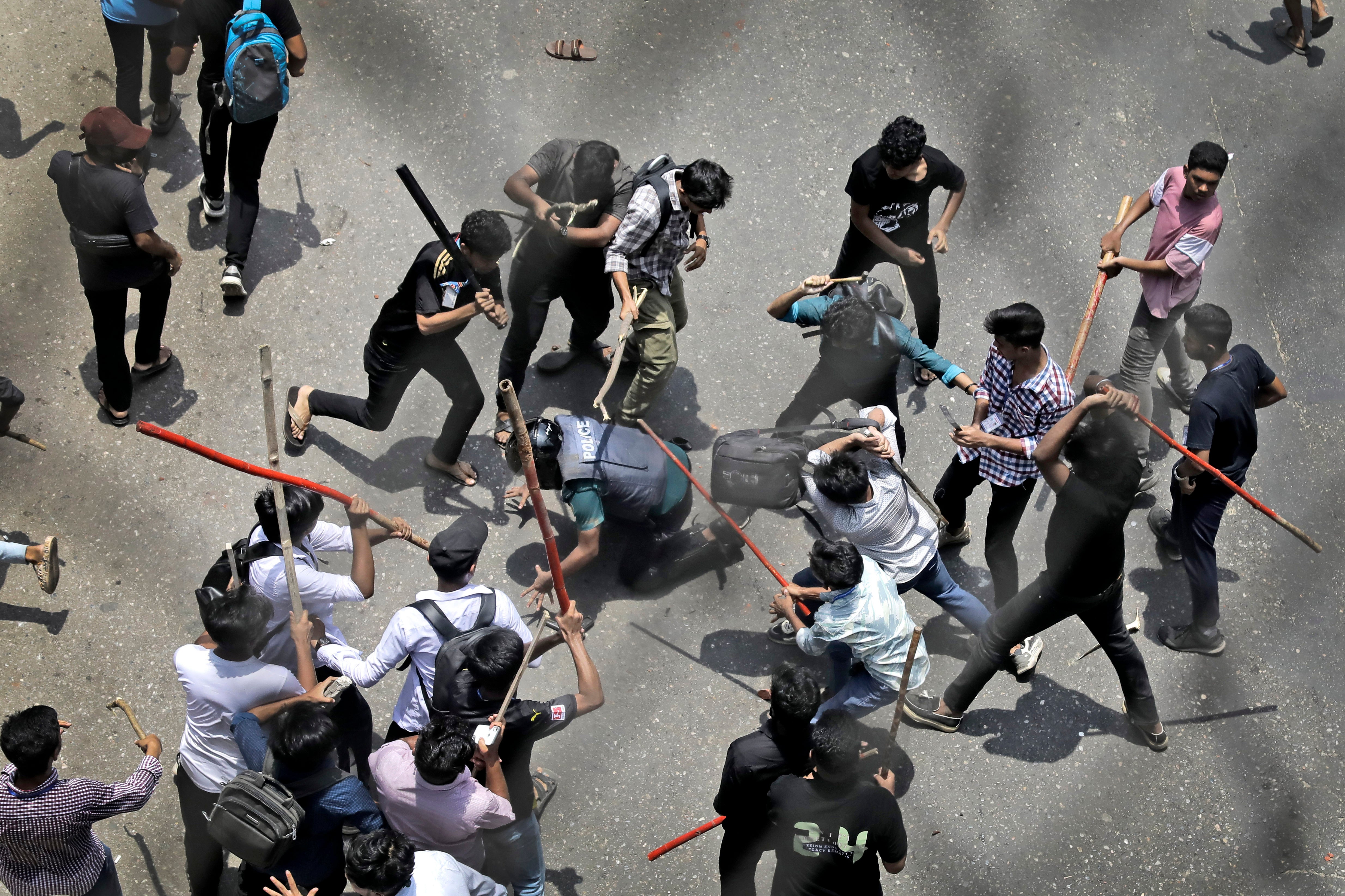 Students beat a policeman with sticks during a protest over a controversial quota system for government job applicants in Dhaka, Bangladesh, on 18 July 2024