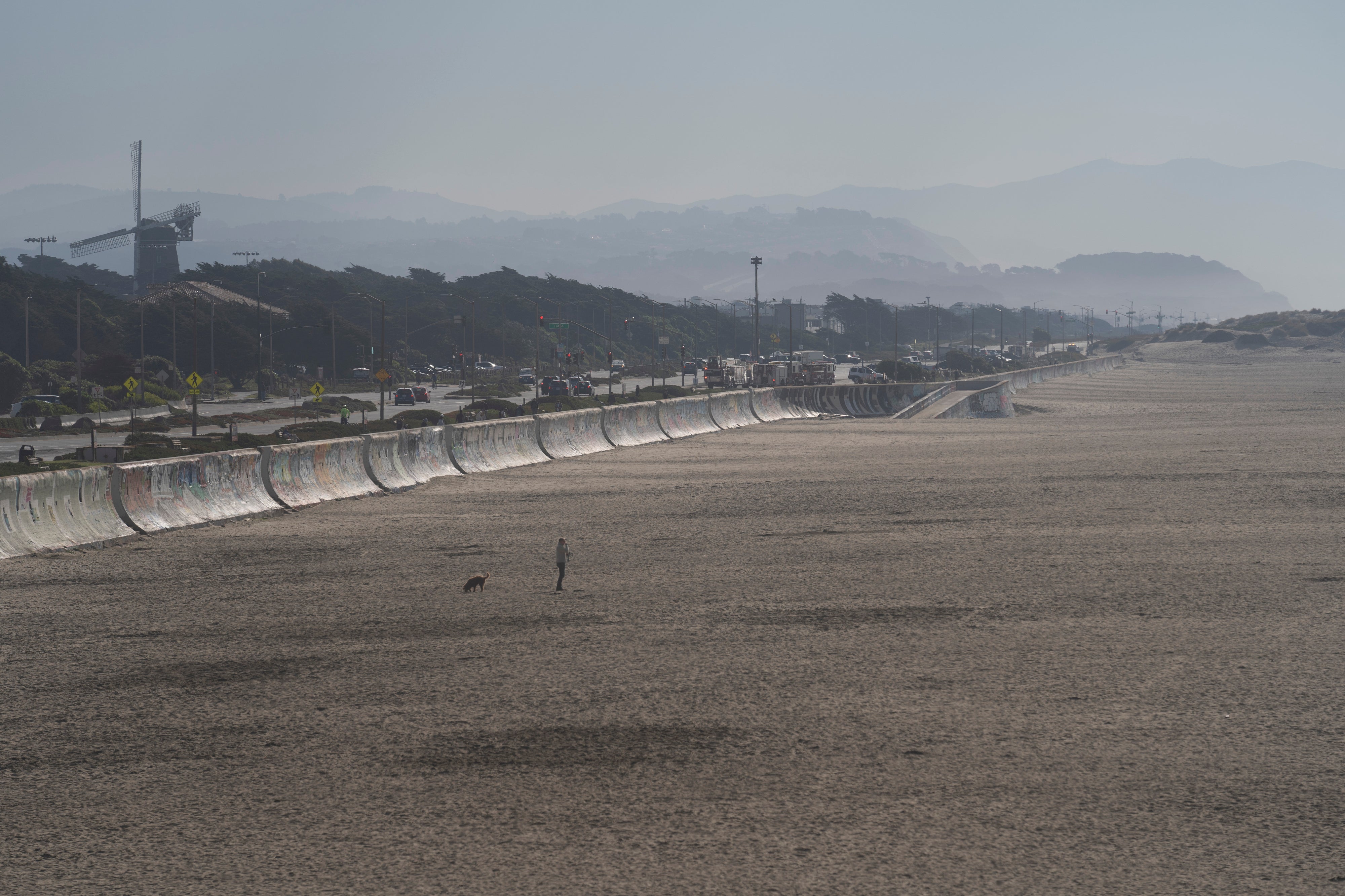 A person and their dog wander along Ocean Beach in San Francisco during a tsunami warning on Thursday, Dec. 5, 2024.