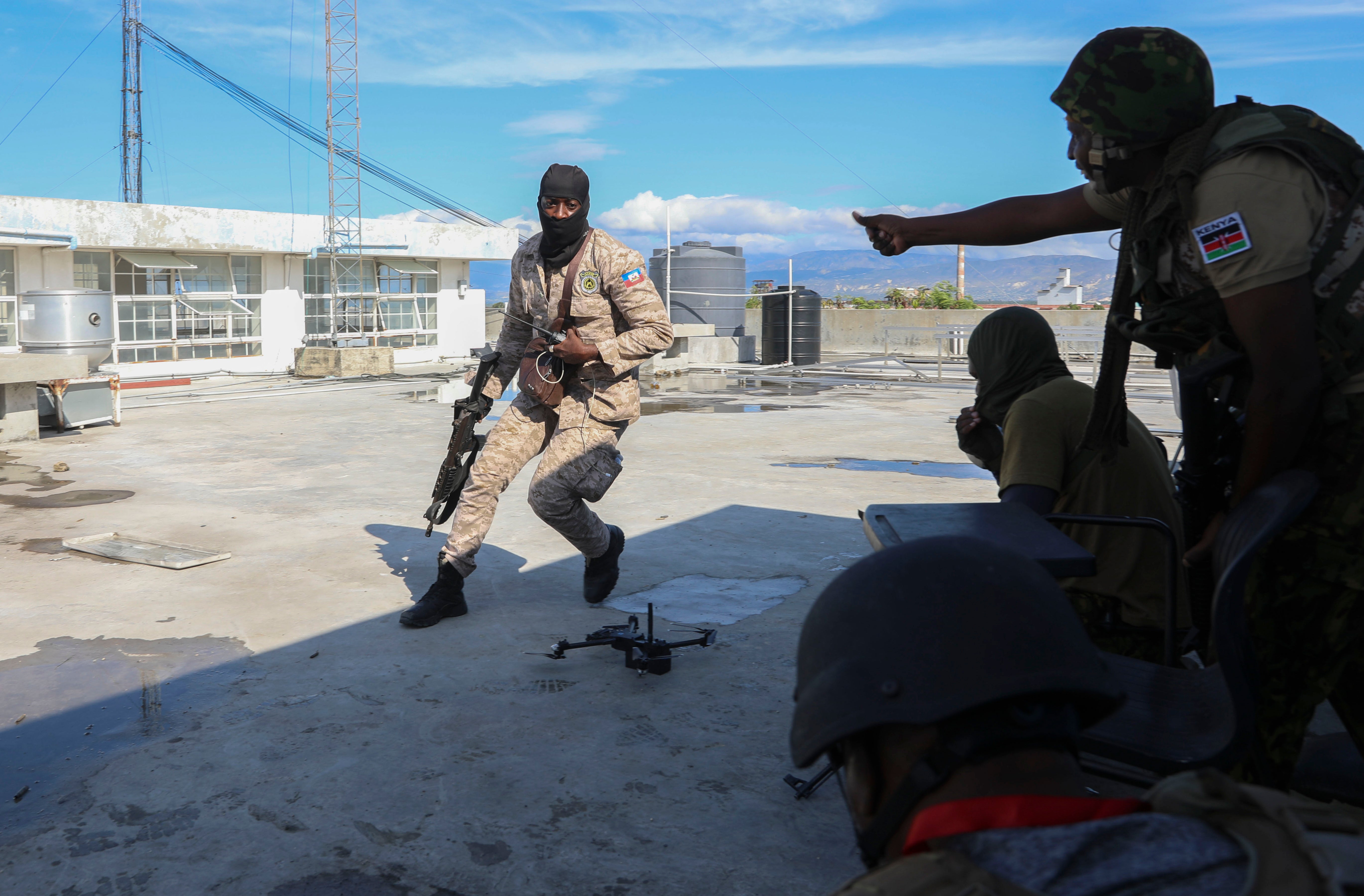 A Haitian police officer runs to take cover with Kenyan police officers, part of a UN-backed multinational force