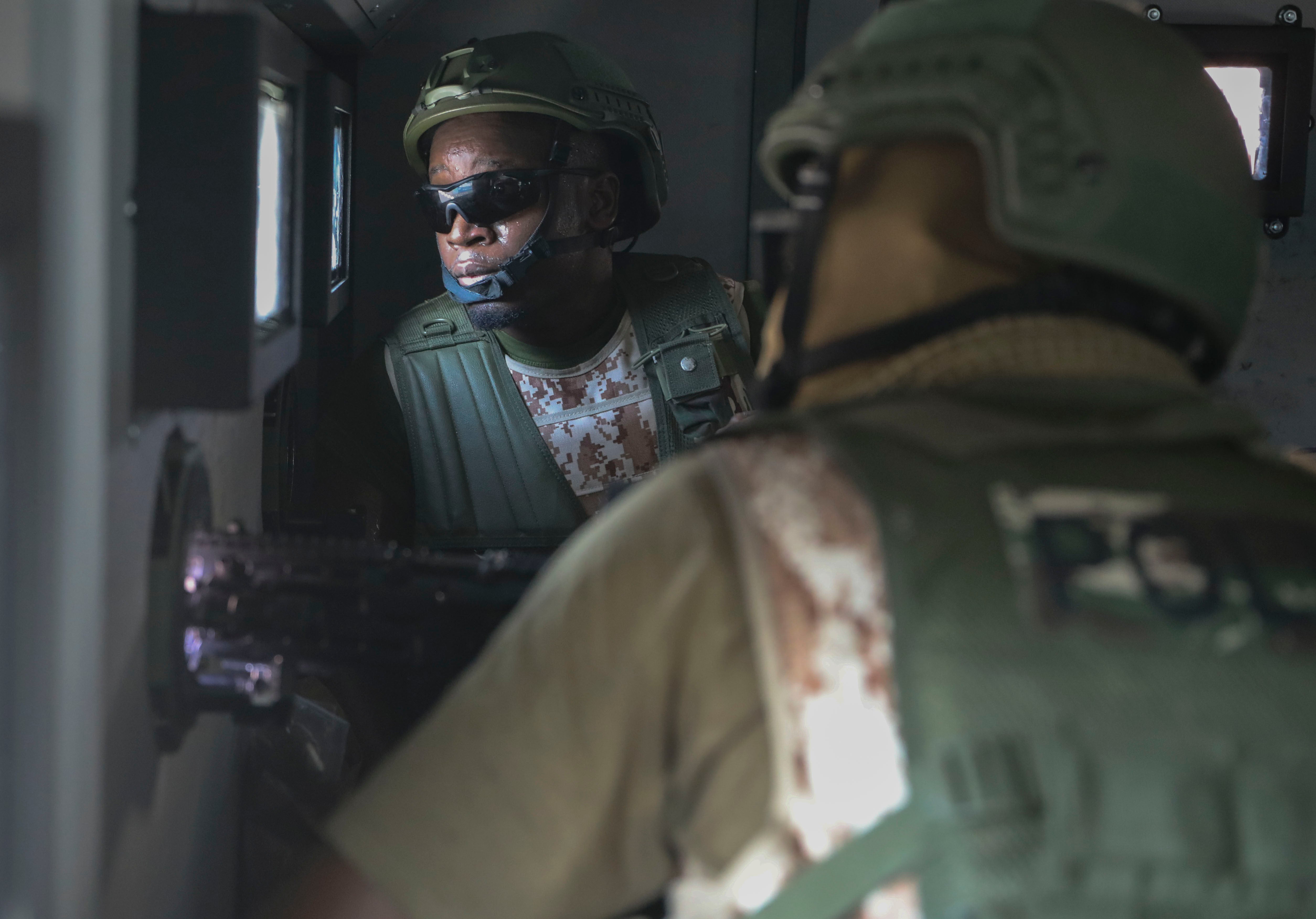 Kenyan police officers, part of a U.N.-backed multinational force, aim weapons out of an armored vehicle in Port-au-Prince