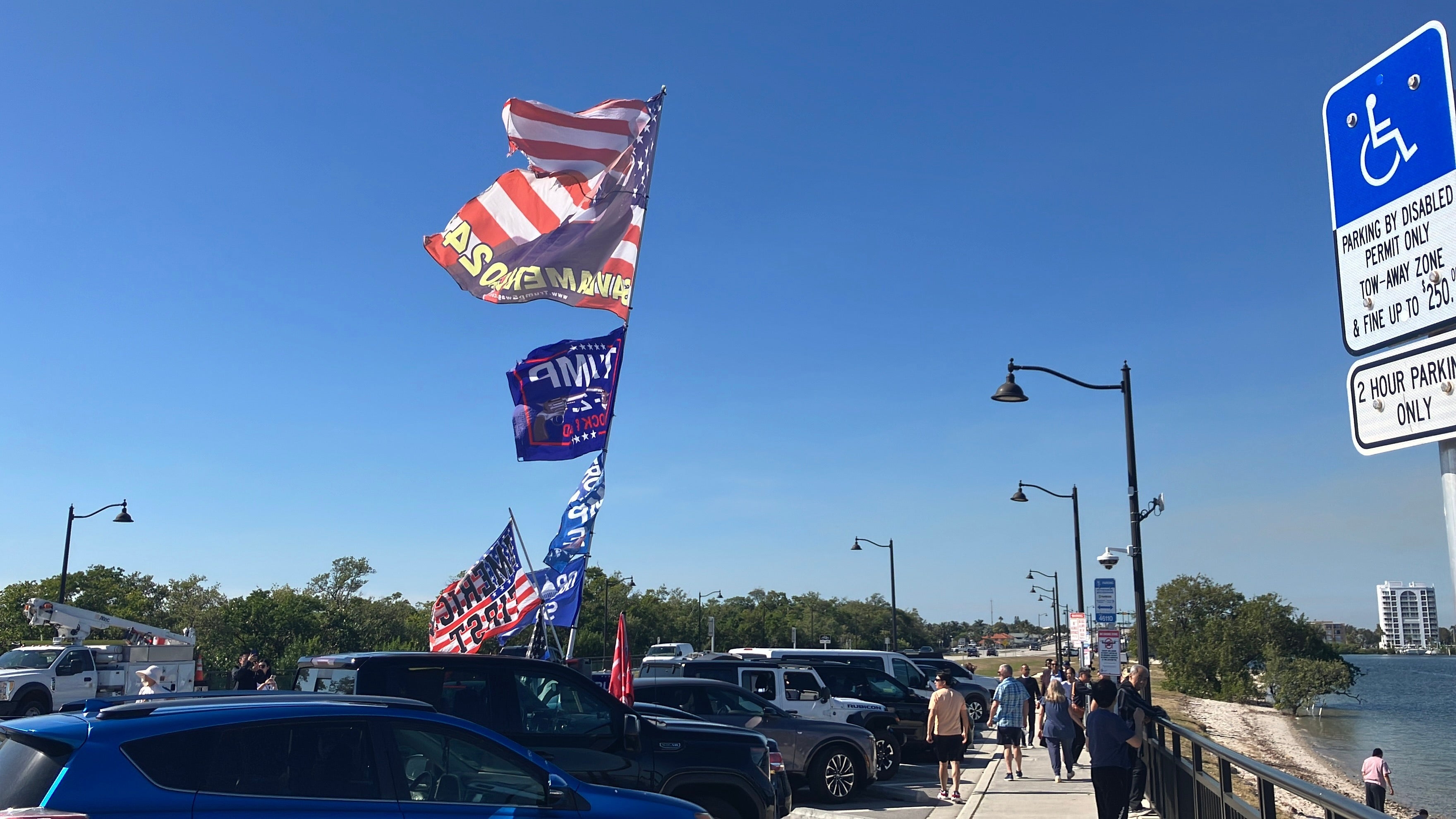 A parking lot by Mar-a-Lago features Trump flags and and a car with Trump paraphenalia.