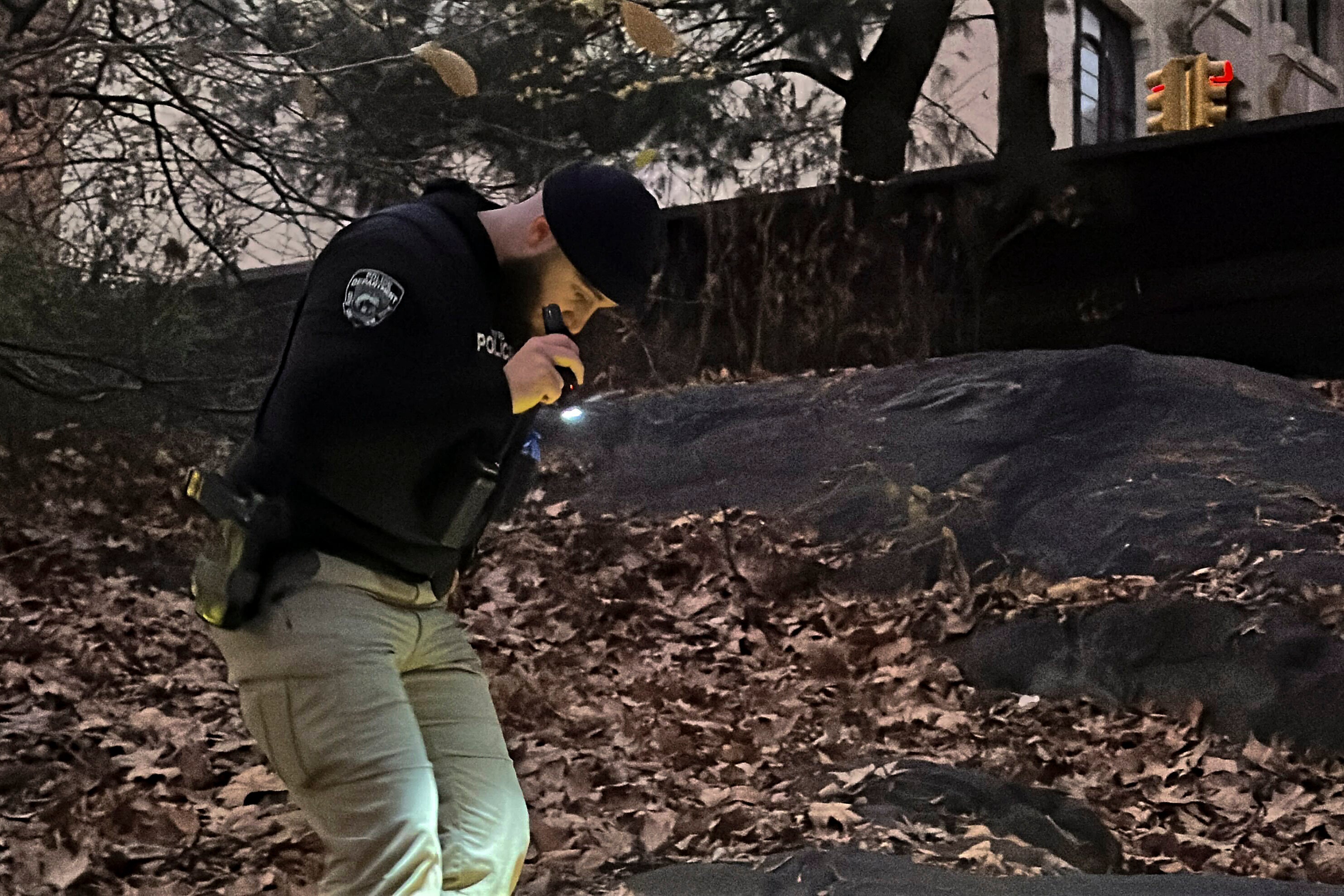 A New York City Police officer walks through brush and foliage in Central Park near 64th Street and Central Park West while searching for a backpack police believe was dropped in the park by the person suspected of killing UnitedHealthcare CEO Brian Thompson