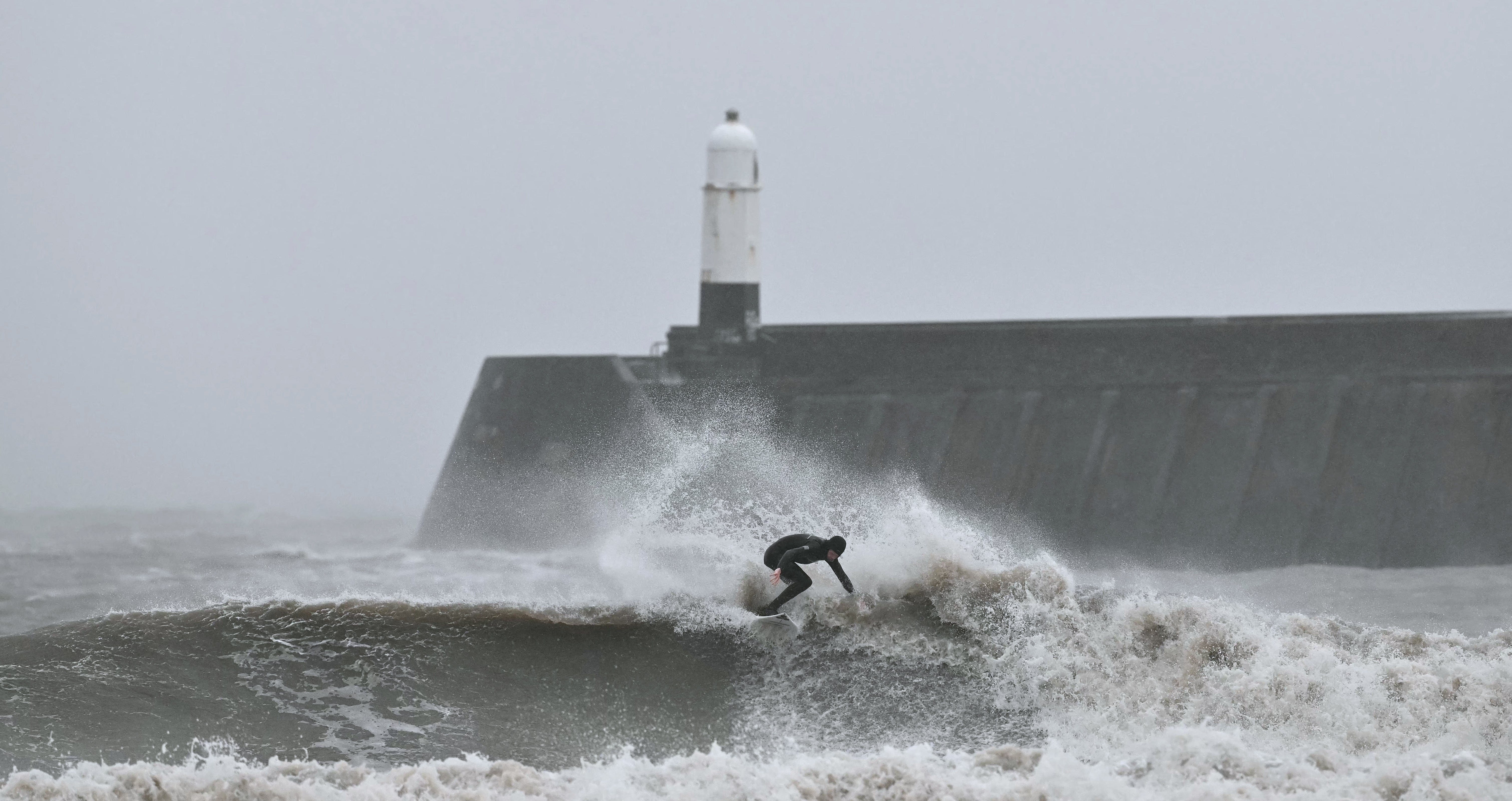 A surfer rides a wave at Porthcawl, south Wales