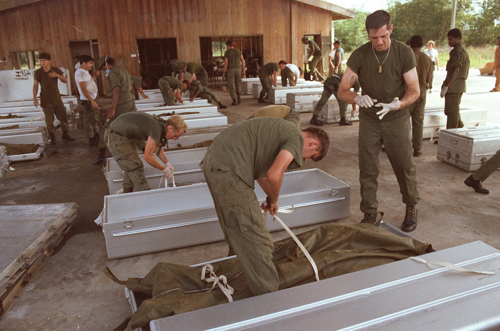 Military personnel place bodies in coffins at the airport in Georgetown, Guyana