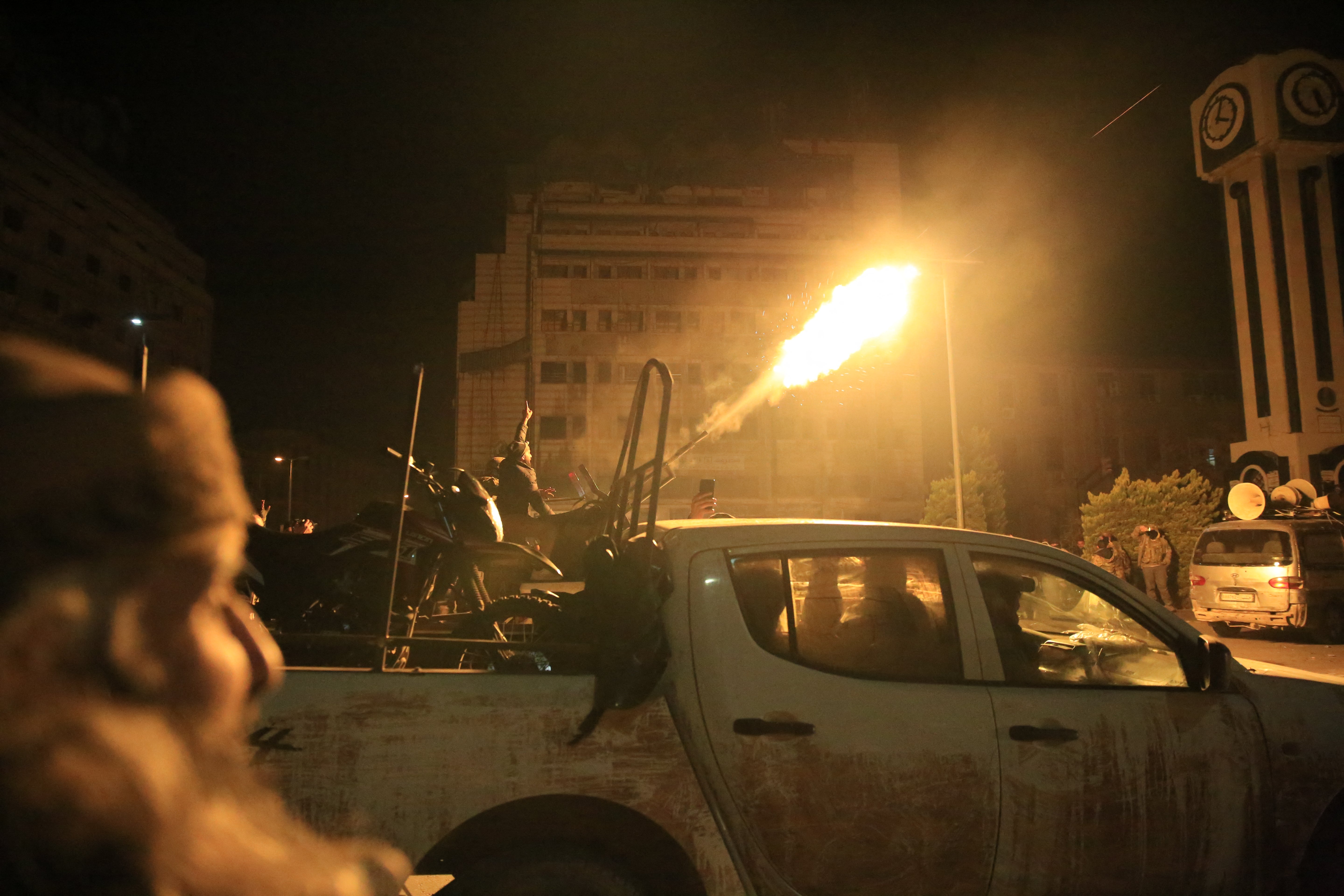 Rebel forces shoot in the air as they parade in their vehicles through the streets of the central Syrian city of Homs