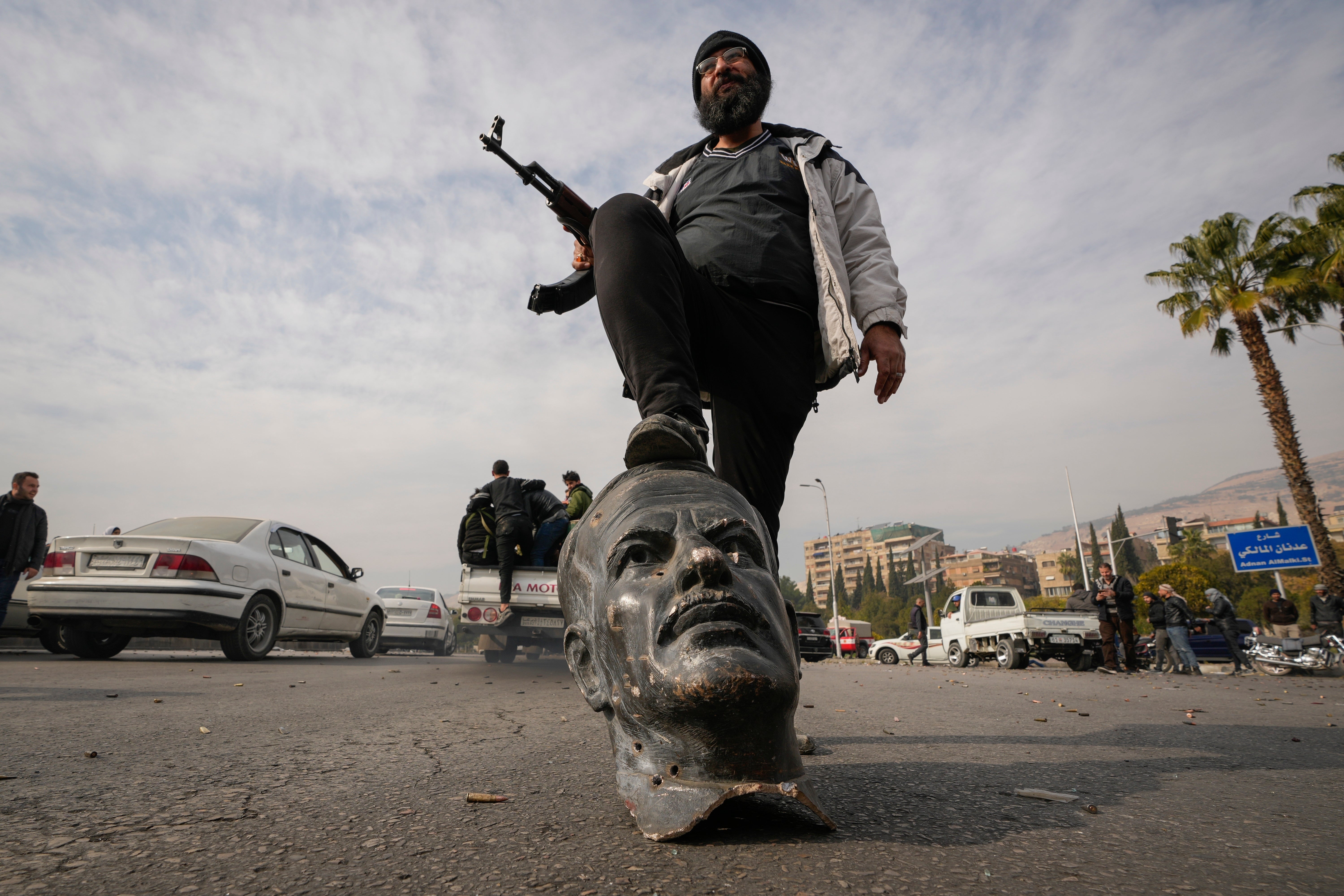 An opposition fighter steps on a broken bust of the late Syrian president Hafez al-Assad