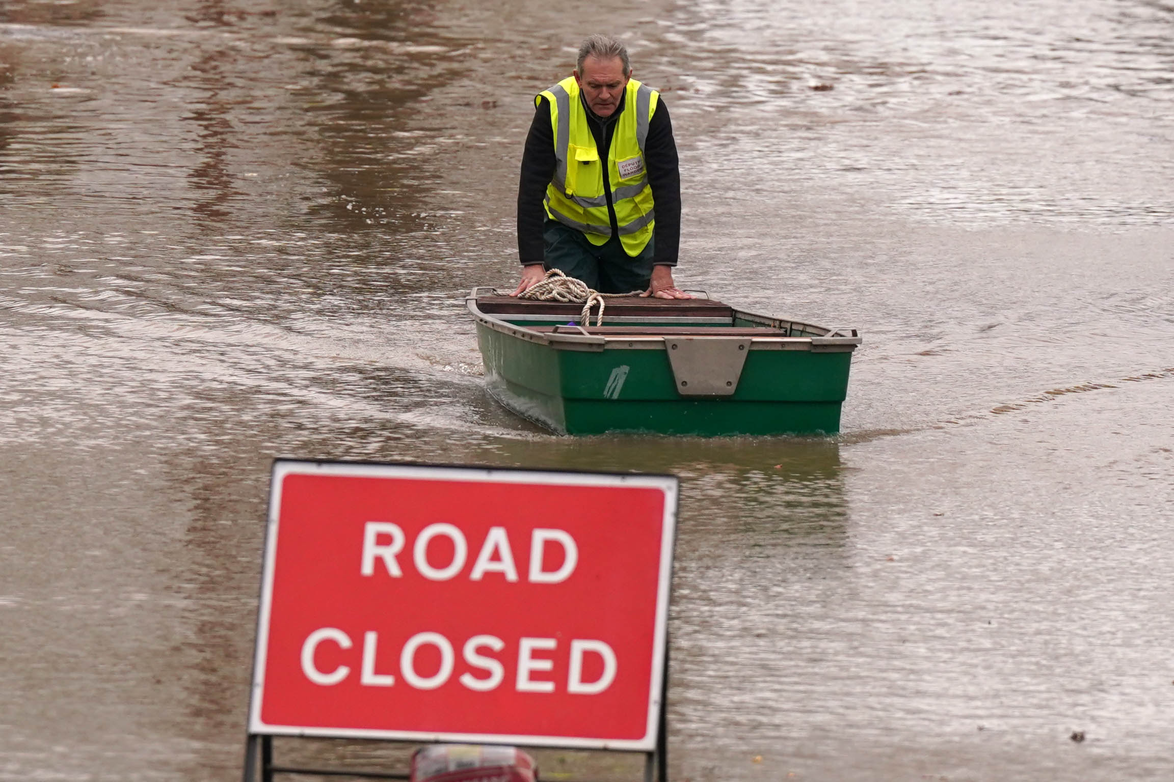 A flood warden pushes a boat in floodwater in Greyfriars Avenue in Hereford