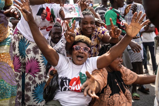 <p>A supporter of former Ghana president and presidential candidate of the National Democratic Congress (NDC) party John Mahama wearing a t-shirt with the party's colours gestures</p>