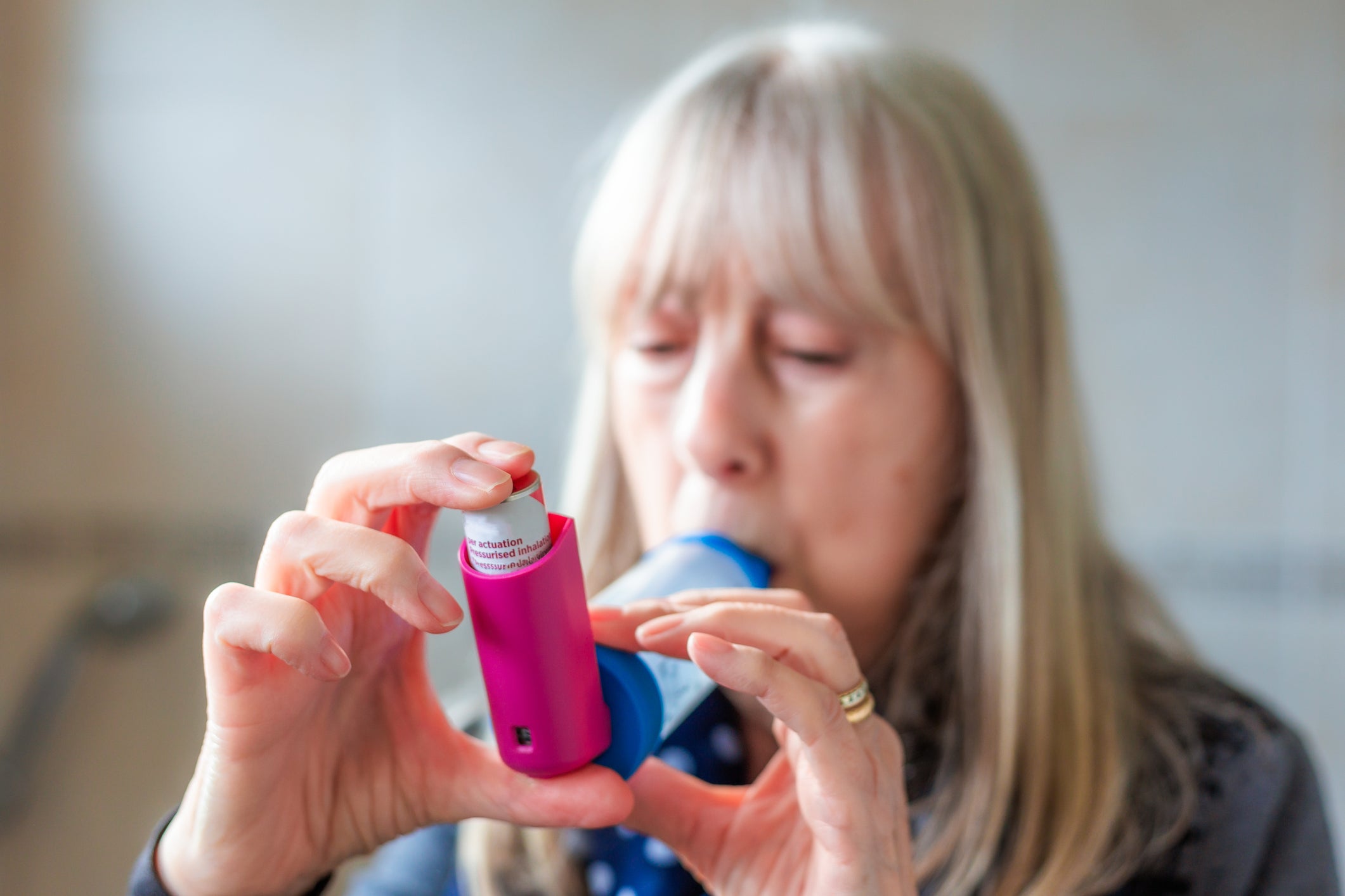 A senior woman uses her inhaler. New research has found that one in six US adults are stopped from taking their asthma medication as it has been prescribed due to its cost