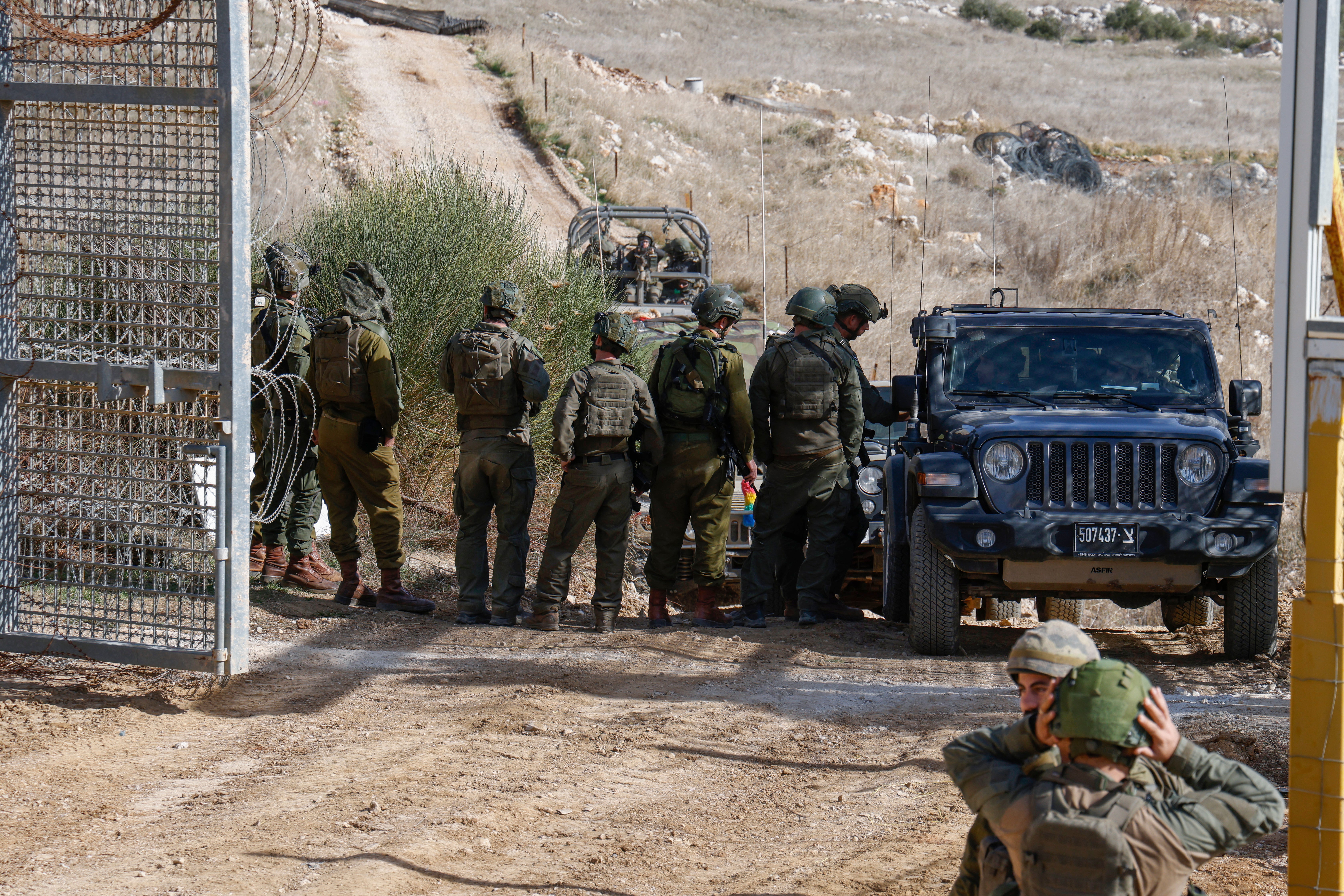 Israeli military vehicles cross the fence as they return from the buffer zone with Syria