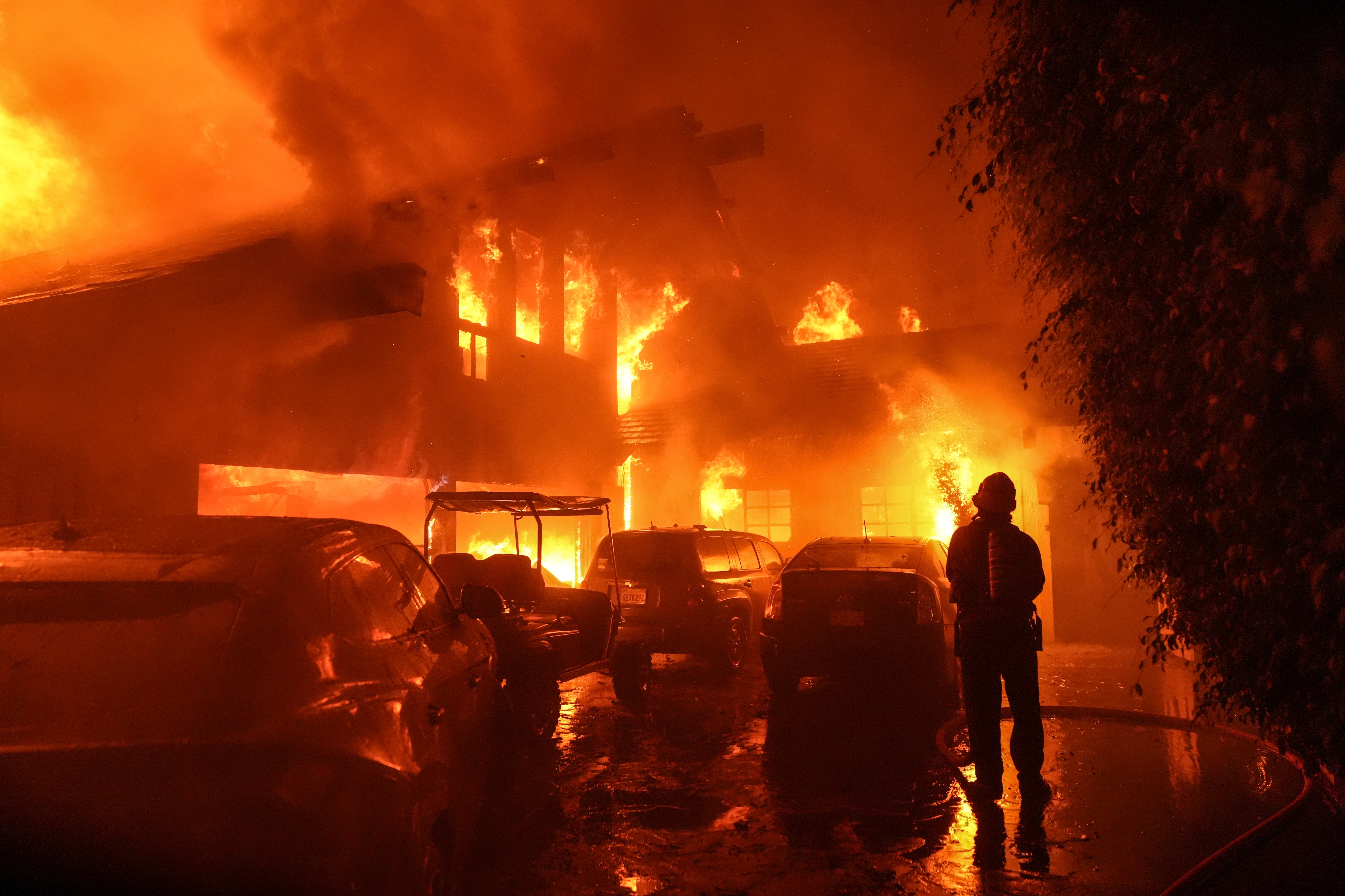 A firefighter sprays water on a house on Tuesday as it burns during the Franklin Fire in Malibu, California. It was unclear how many homes had already been affected