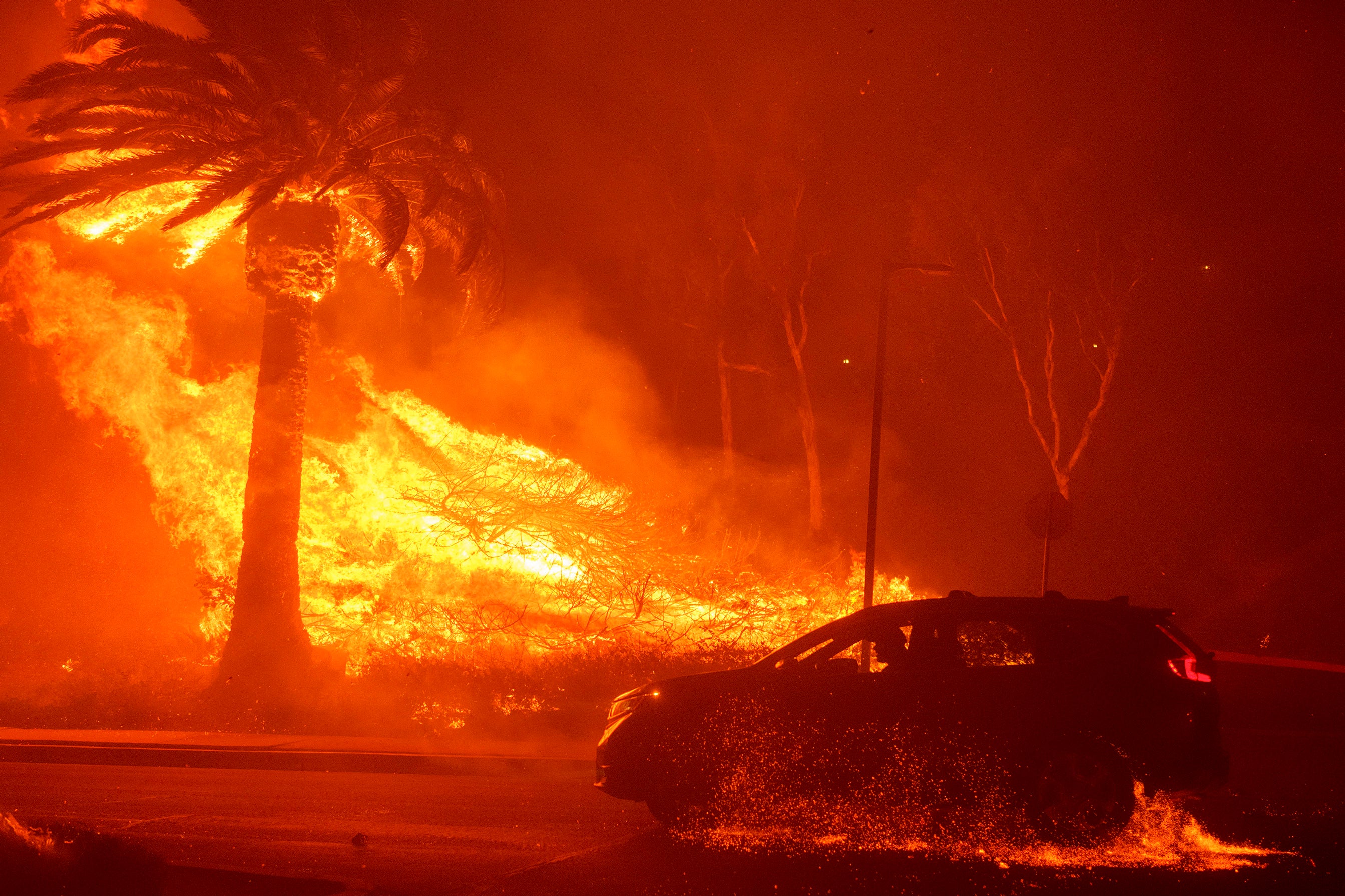 A car drives past flames from the Franklin Fire at Pepperdine University in Malibu