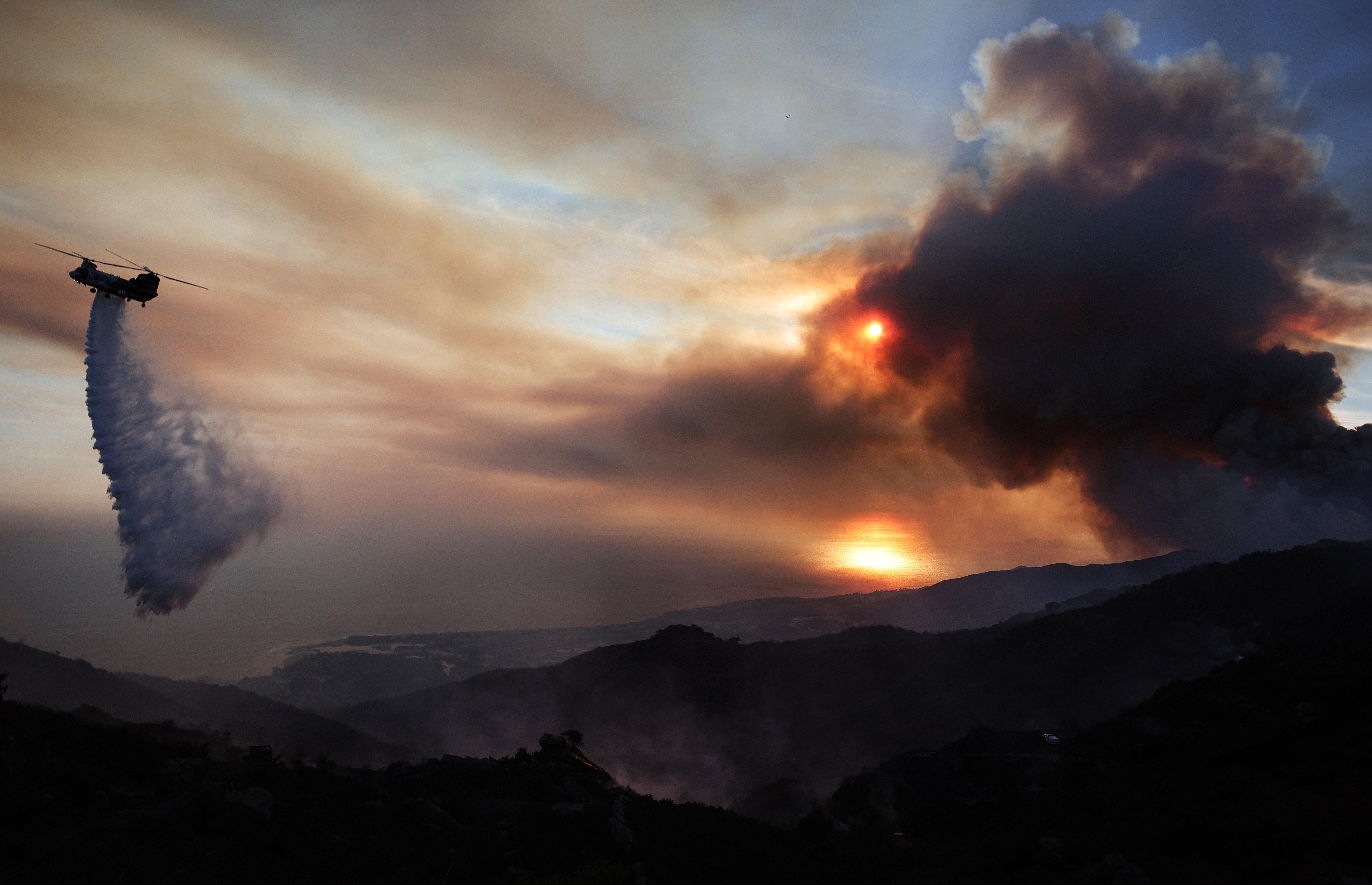 A firefighting helicopter drops water as the Franklin Fire continues to burn