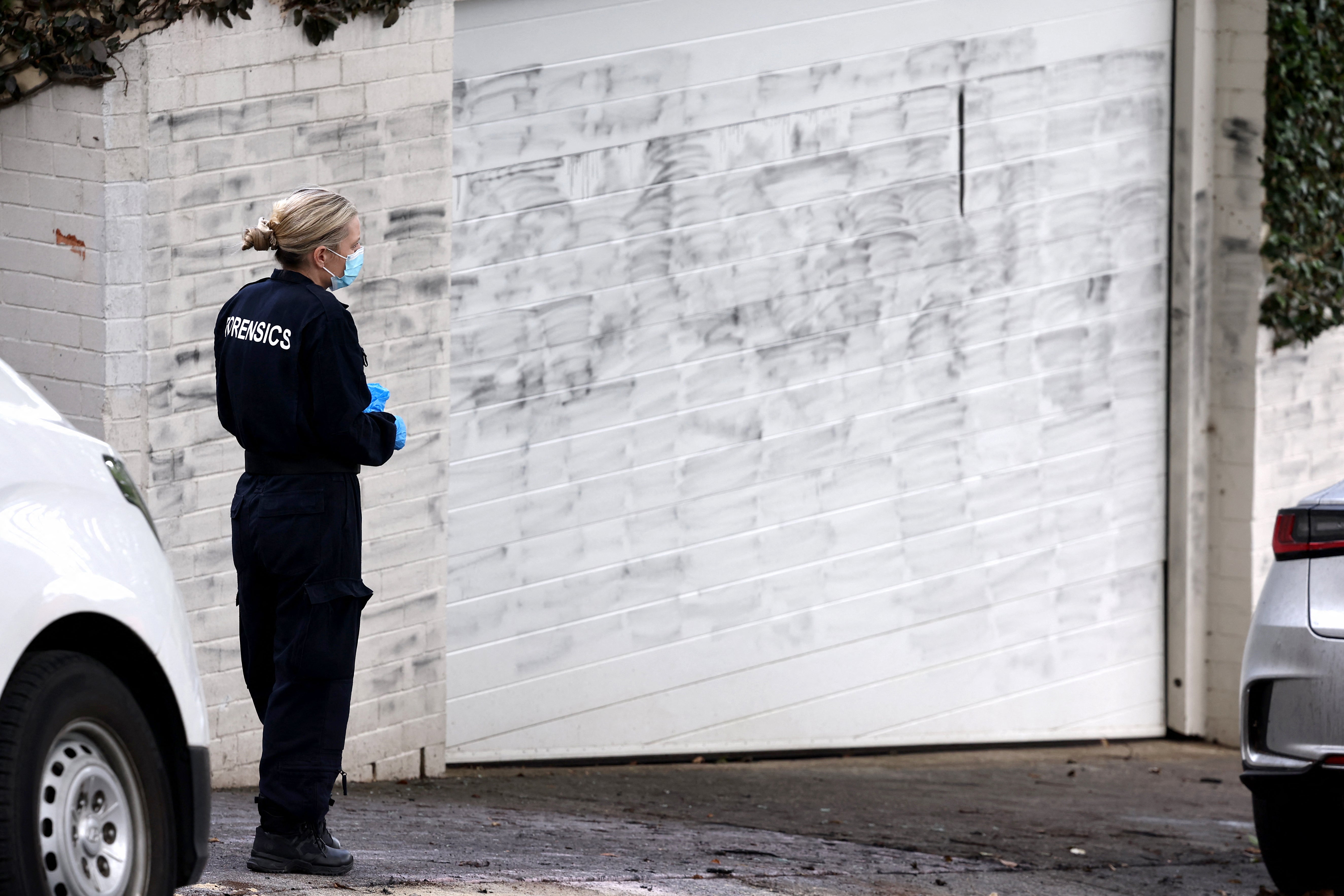 A forensics police officer stands in front of the wall where anti-Israel graffiti has been removed in the Sydney suburb of Woollahra