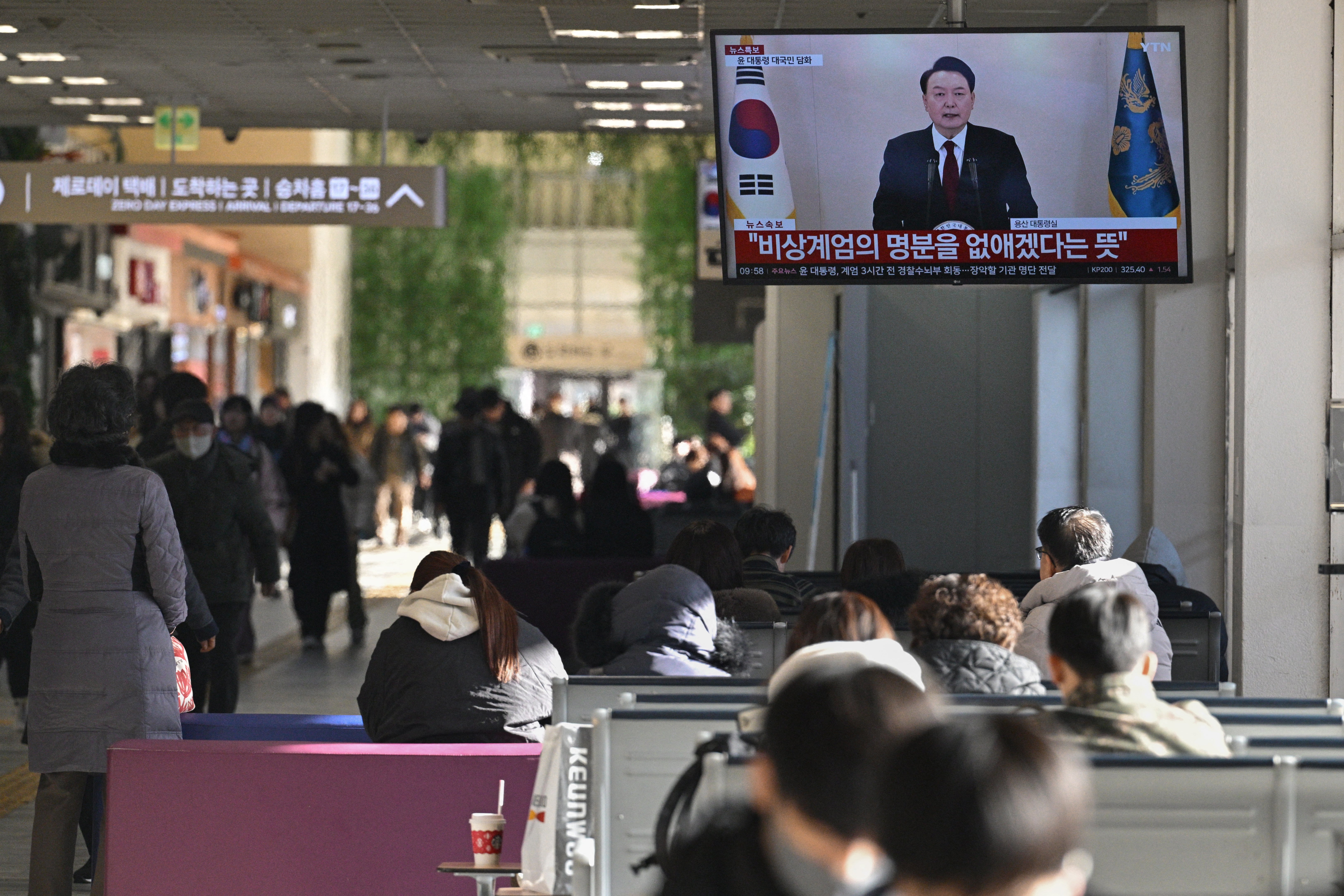 A screen shows South Korean president Yoon Suk Yeol speaking during a televised address at a bus terminal in Seoul on 12 December 2024