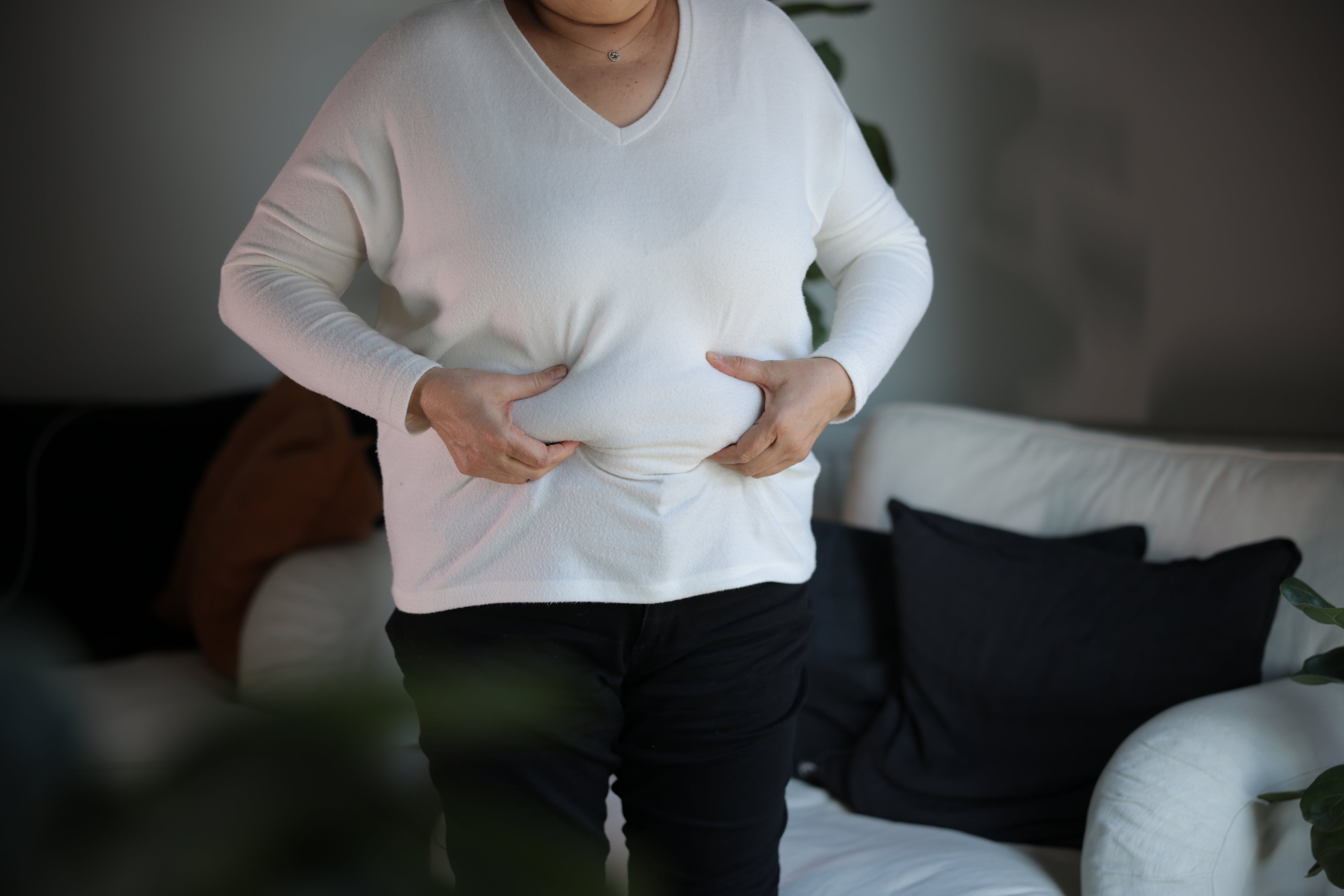 A woman squeezes the fat around her abdomen. A new study has shown obesity and body mass index in the US have decreased for the first time in more than a decade