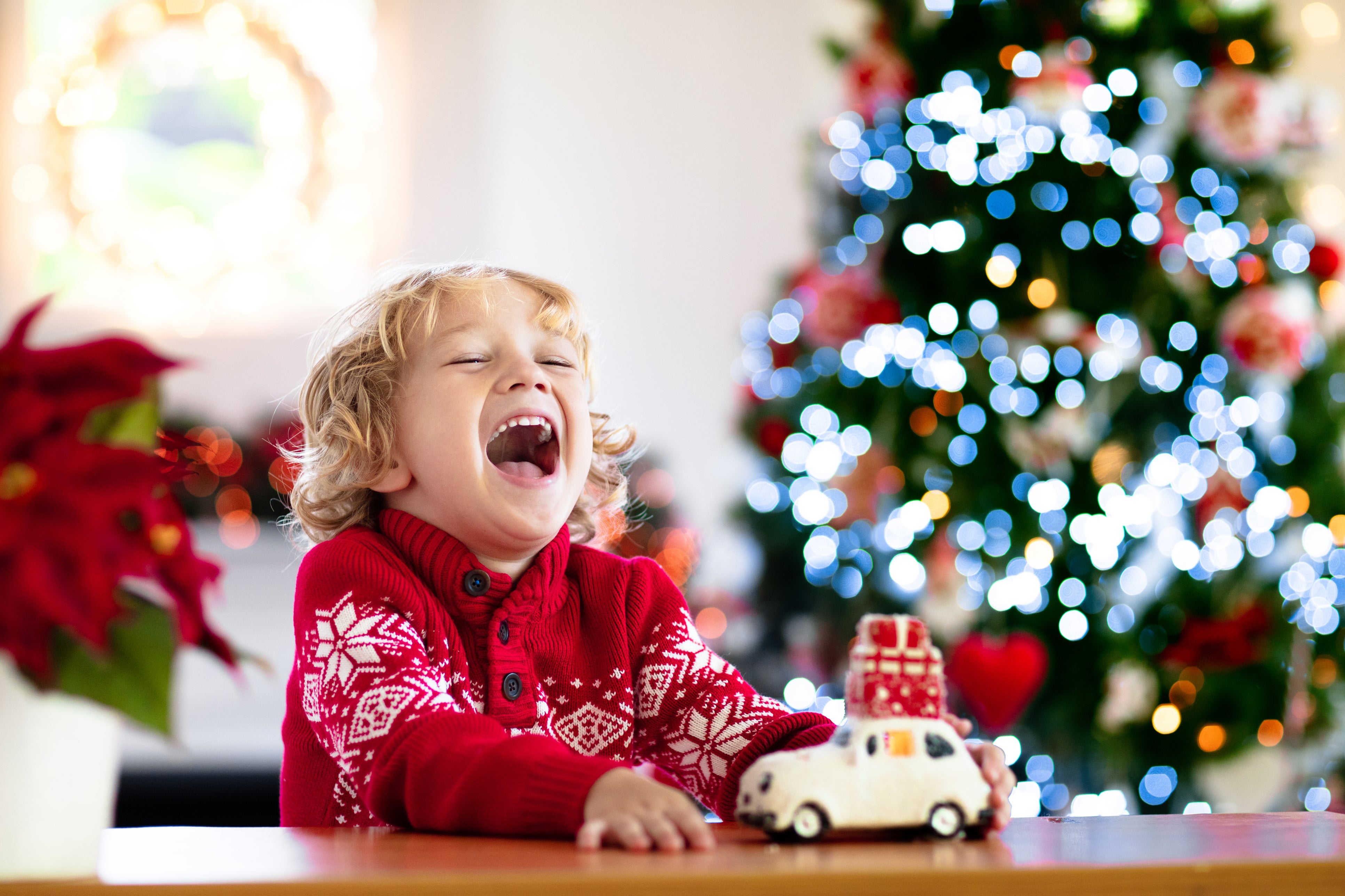 A young boy cries as he plays with a toy in front of a Christmas tree. For preschool-aged children, parents are advised to use logical and immediate consequences for bad behavior