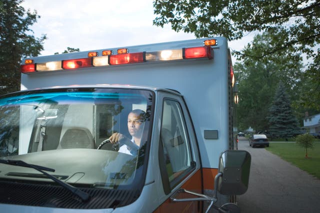 <p>A male ambulance driver is seen driving through a residential area. A new study found ambulance and taxi drivers had the lowest proportion of deaths from Alzheimer’s disease compared to hundreds of other occupations </p>