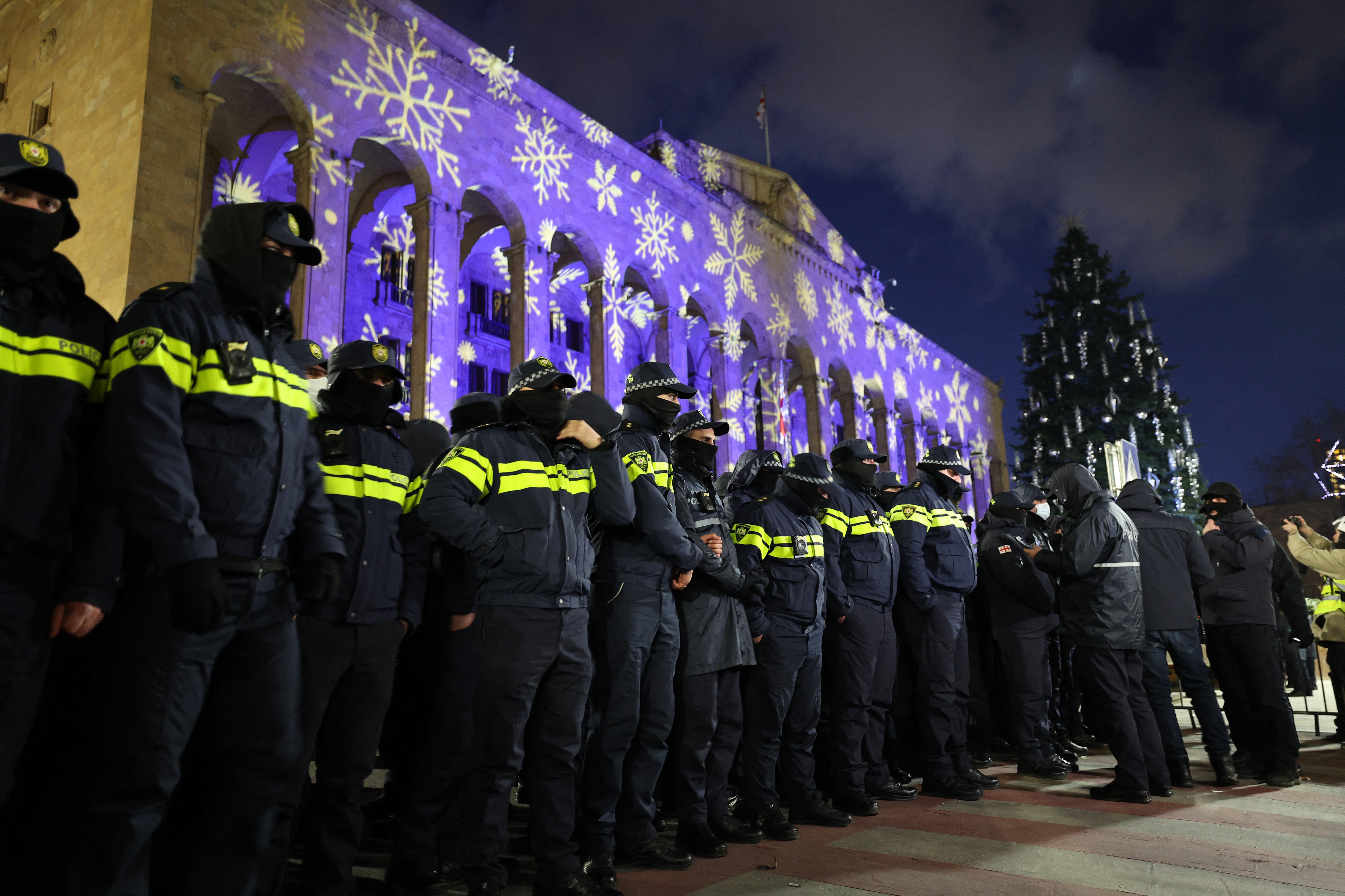 Police officers block the Georgian parliament building in Tbilisi as anti-government demonstrators gather outside