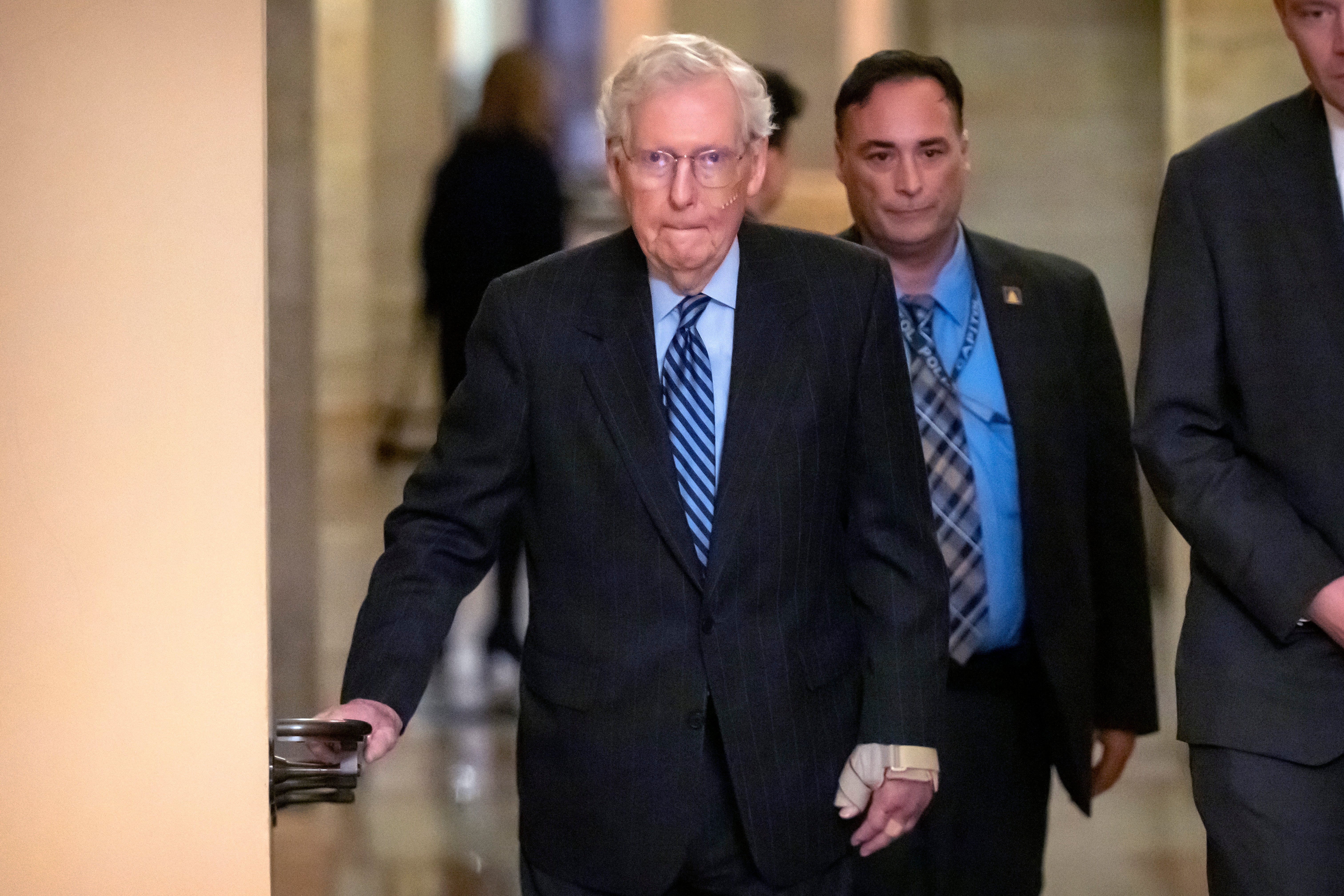 Senate Minority Leader Mitch McConnell of Ky., left, wears a bandage on his face and wrist as he walks to cast a vote last week.