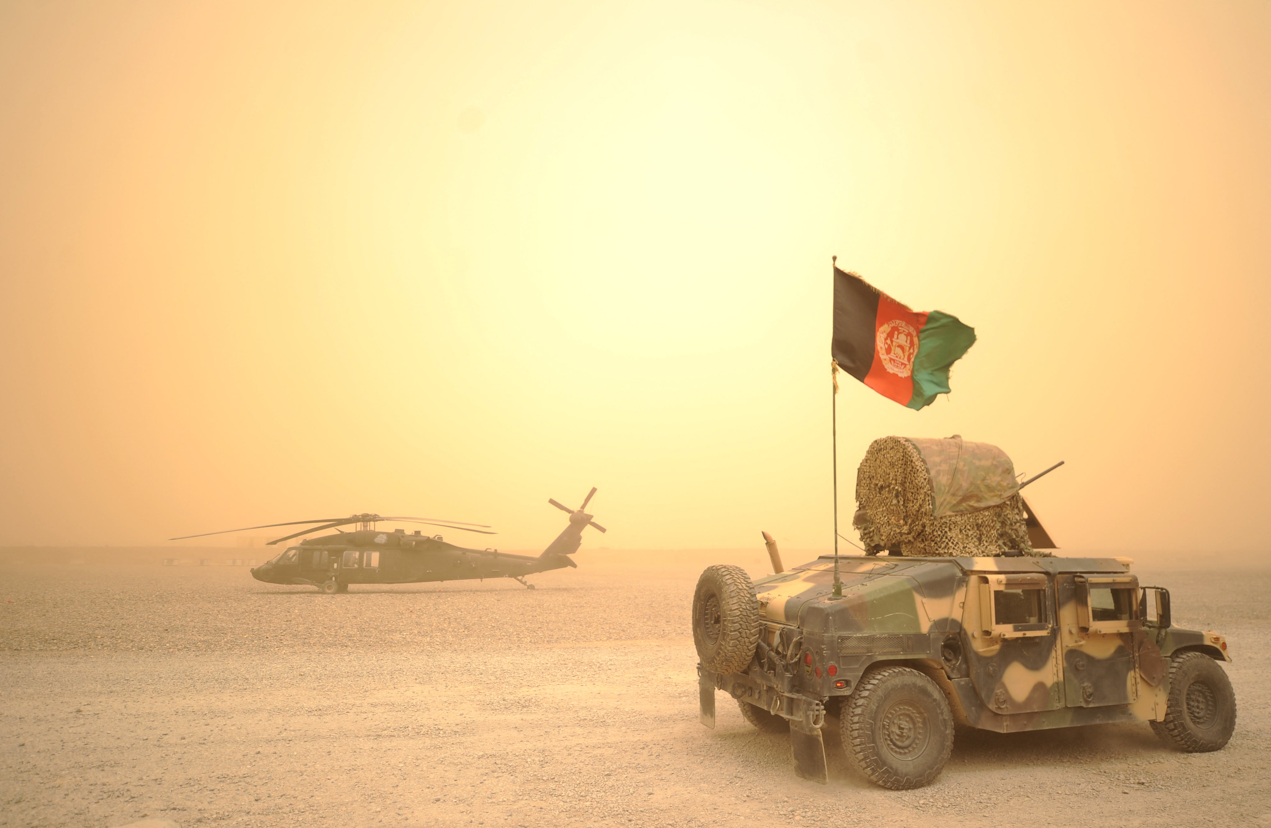 An Afghan national army Humvee drives past a US army Black Hawk helicopter in Kandahar