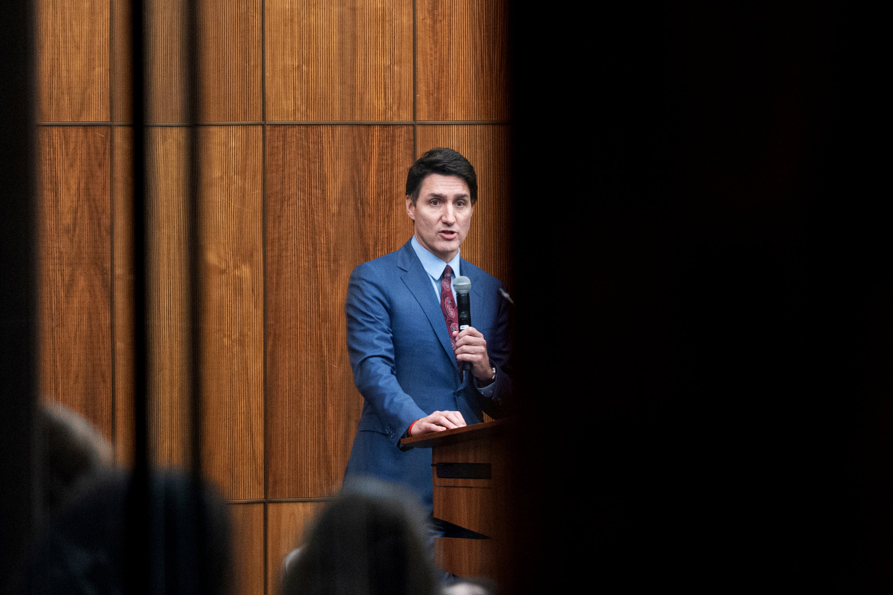 Canada's Prime Minister Justin Trudeau is pictured through glass as he speaks with members of his caucus in Ottawa, Ontario, on Monday