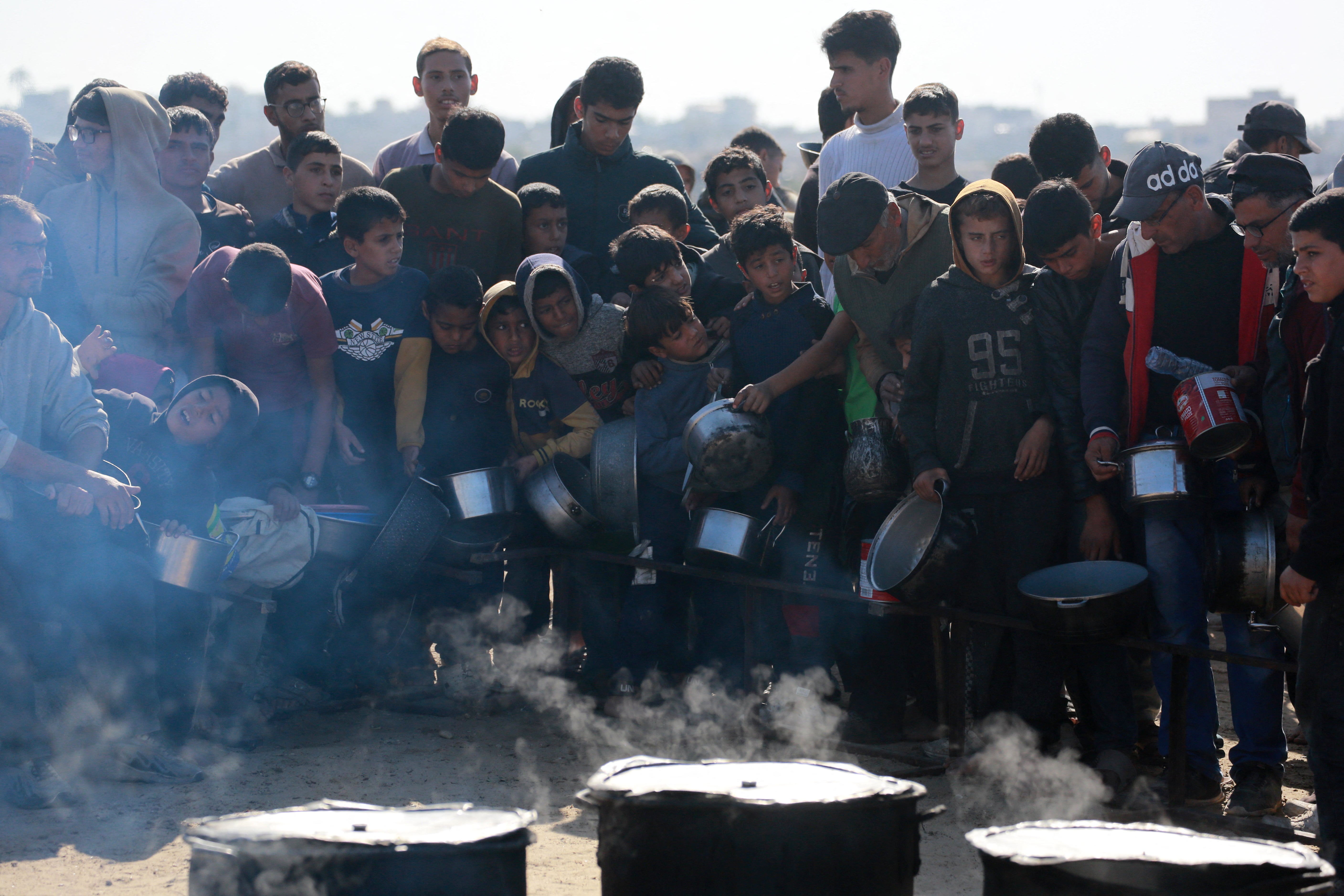 Palestinians stand and wait for food at a distribution centre in Gaza