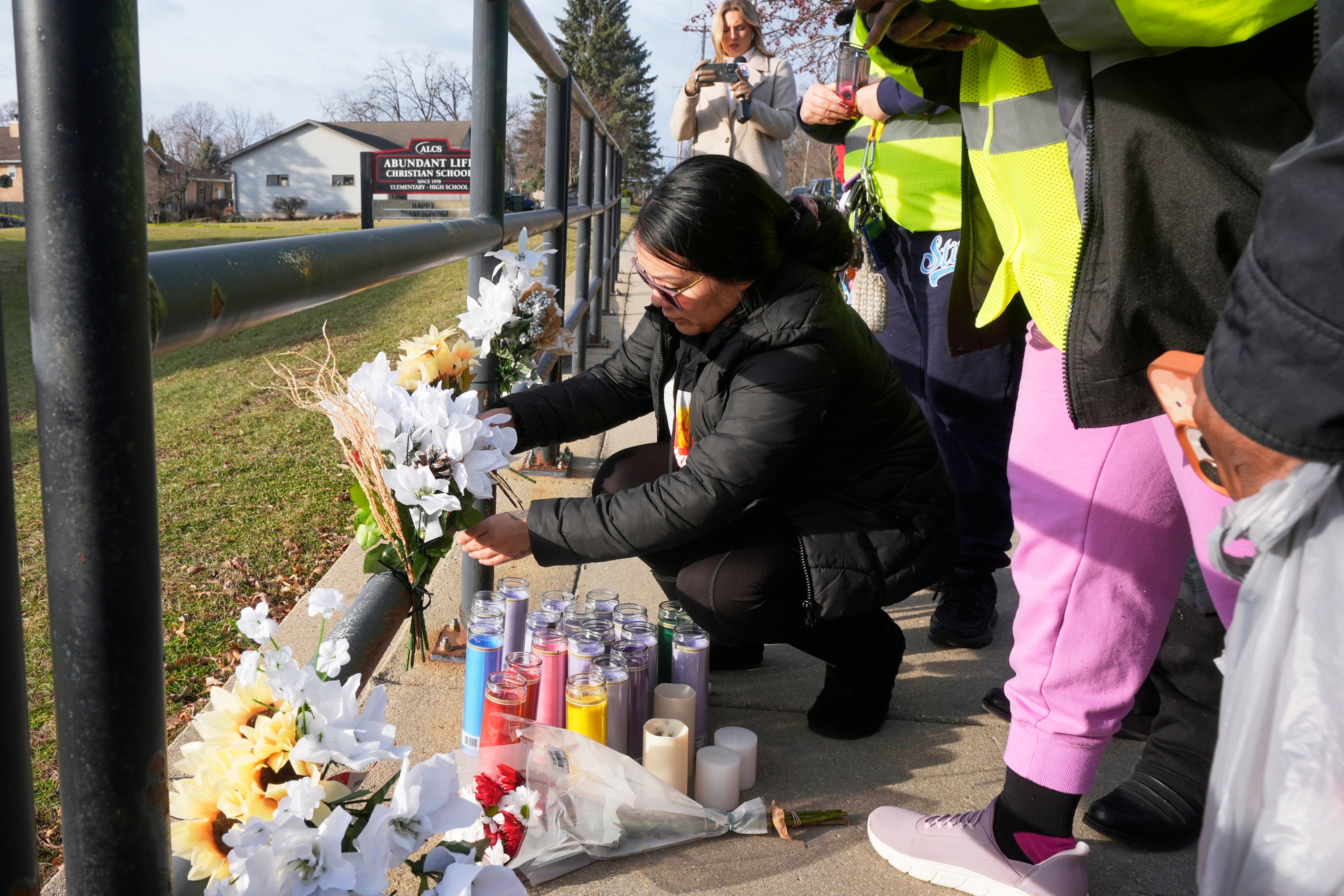 A resident places some flowers outside the Abundant Life Christian School on Tuesday, following the deadly shooting on Monday