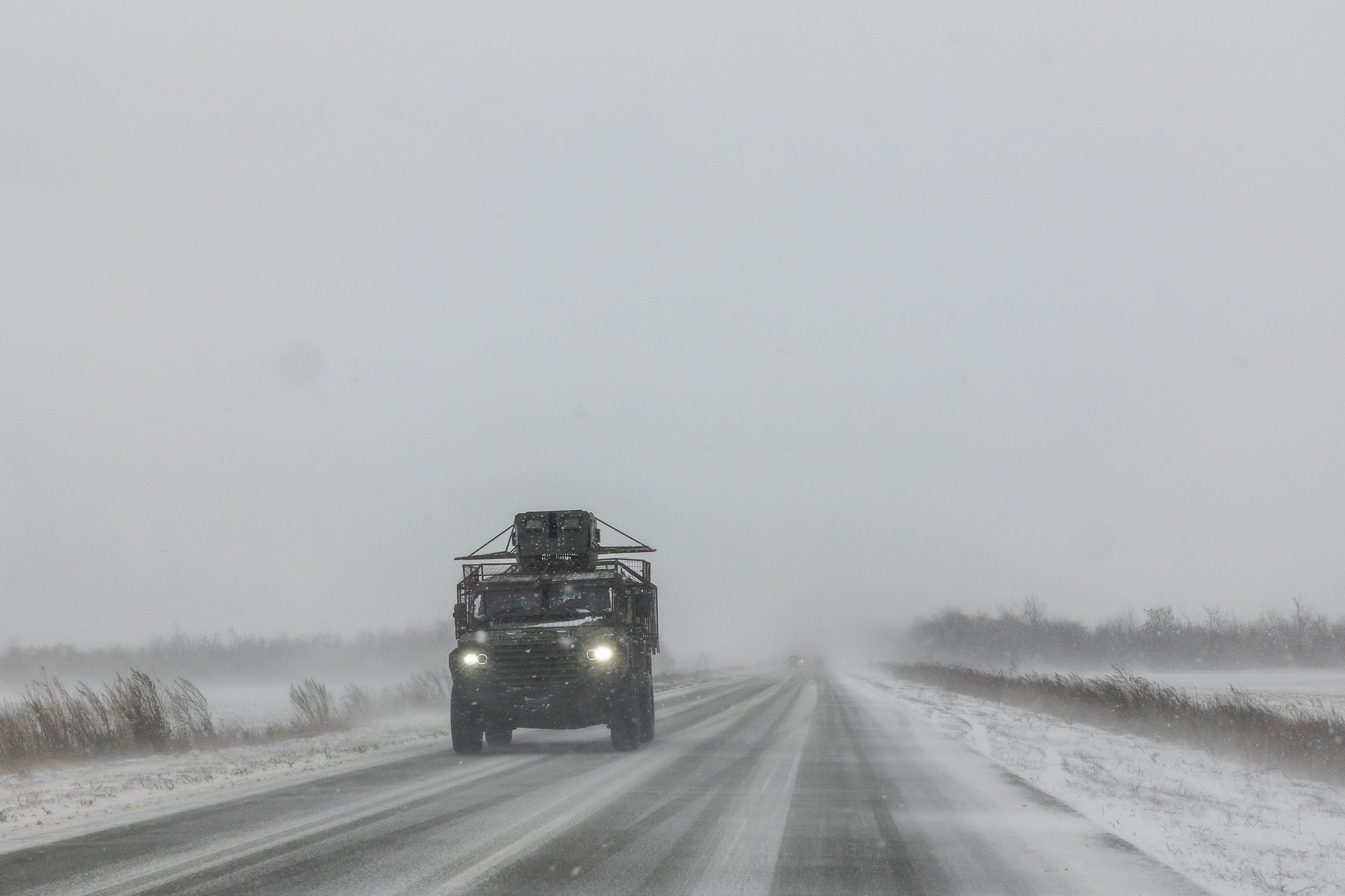 A Ukrainian armoured military vehicle drives along a road during snowfall in eastern Donetsk