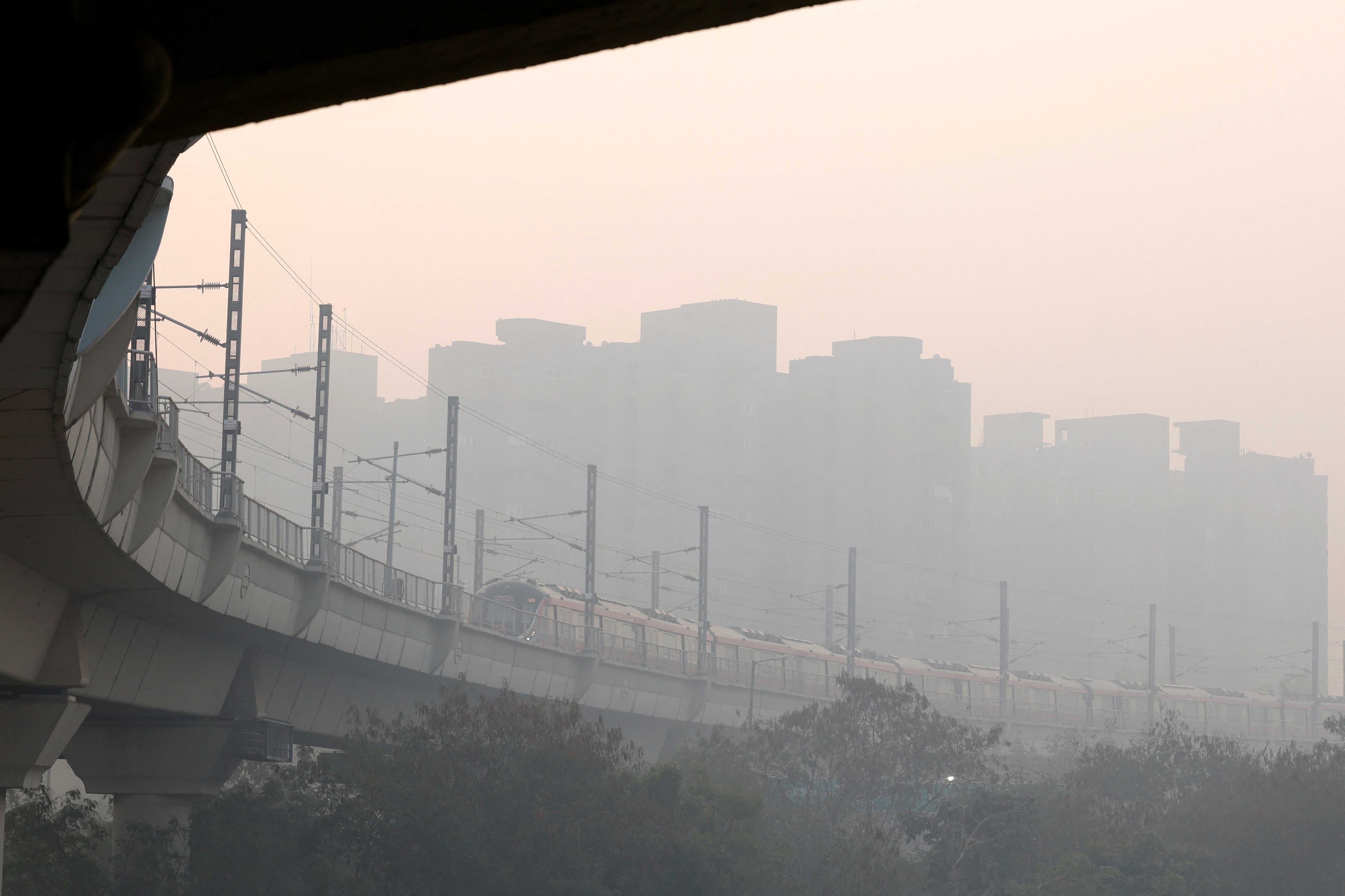 A metro train passes through as the sky is enveloped in smog caused by air pollution in Delhi