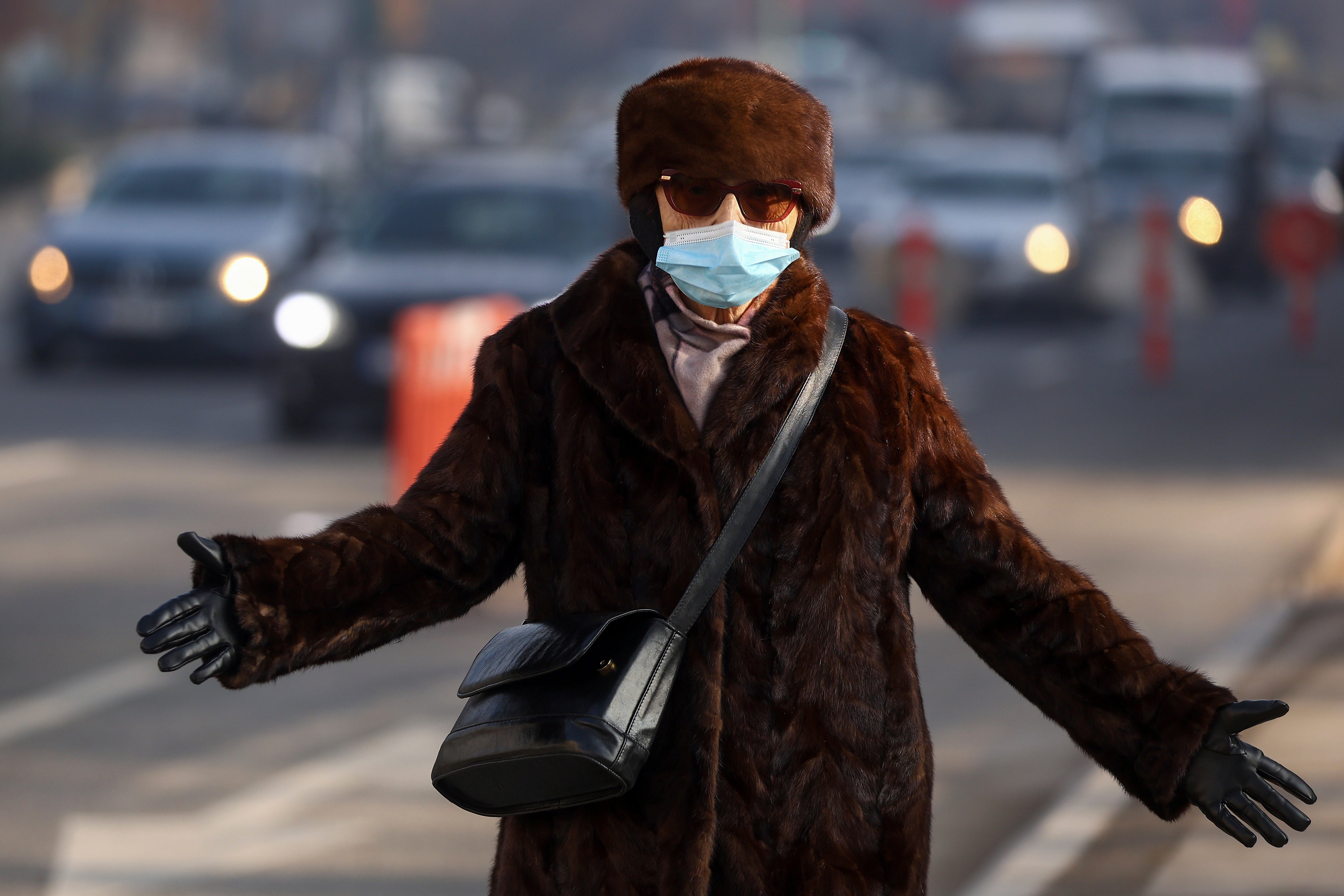 A woman wears a face mask shrouded by pollution haze as smog covers Sarajevo