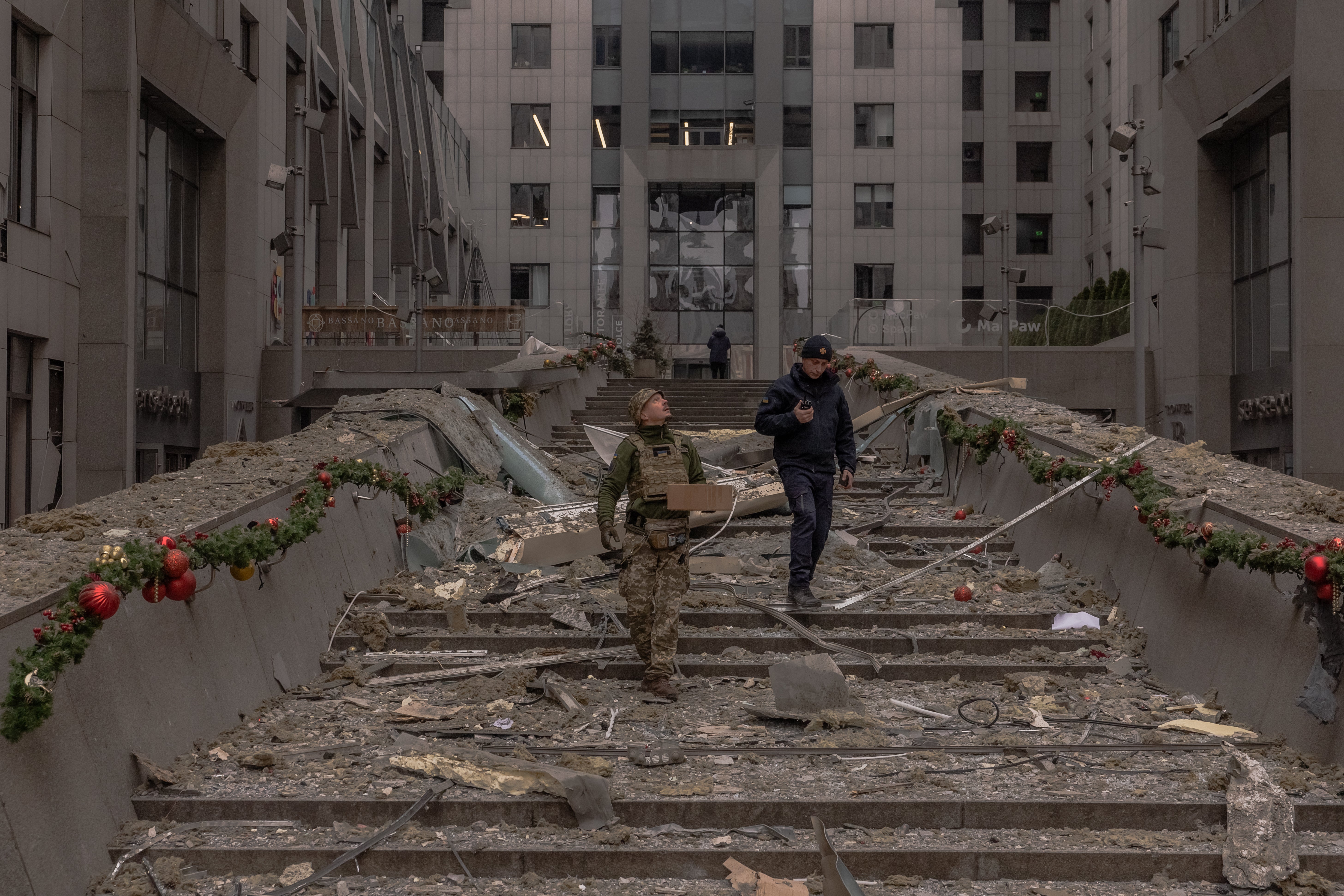 Ukrainian law enforcement officers inspect damage to a building following a missile attack in Kyiv