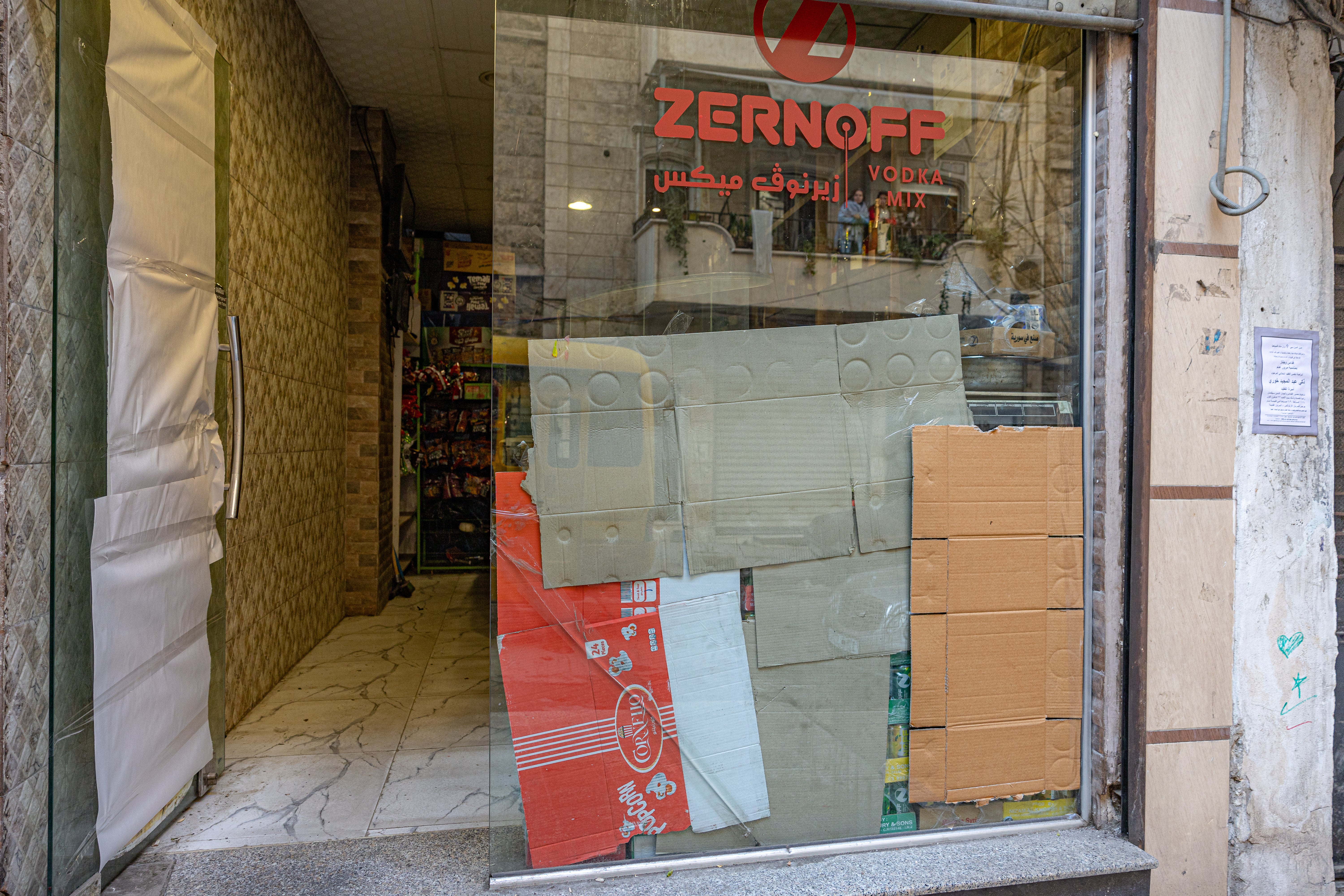 Alcohol stores in Aleppo cover their glass frontages with cardboard after being told to remove signs by rebel fighters