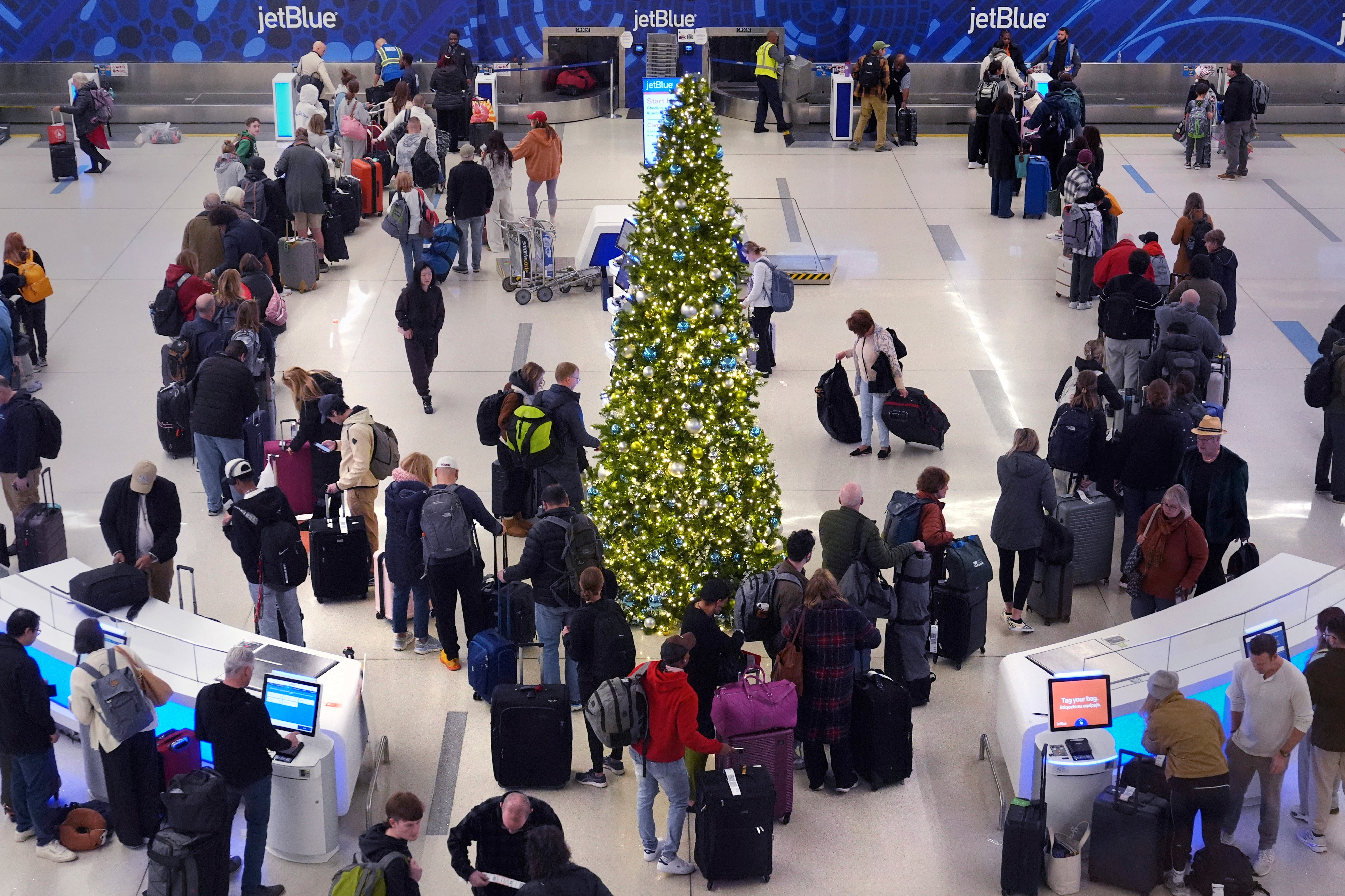 Holiday travelers wait in line to check their bags on Friday at Boston’s Logan International Airport. More than 6,100 delays have been reported at airports around the country