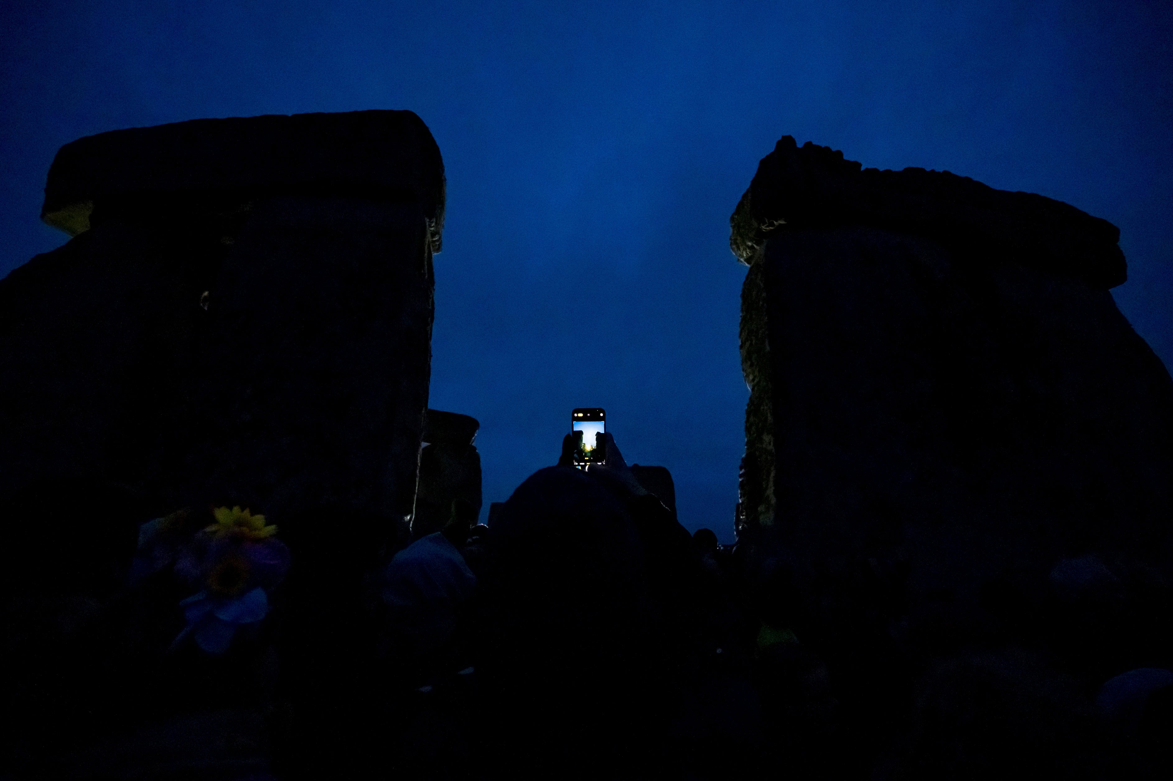 A person holds up a smartphone in the gloom ahead of sunrise