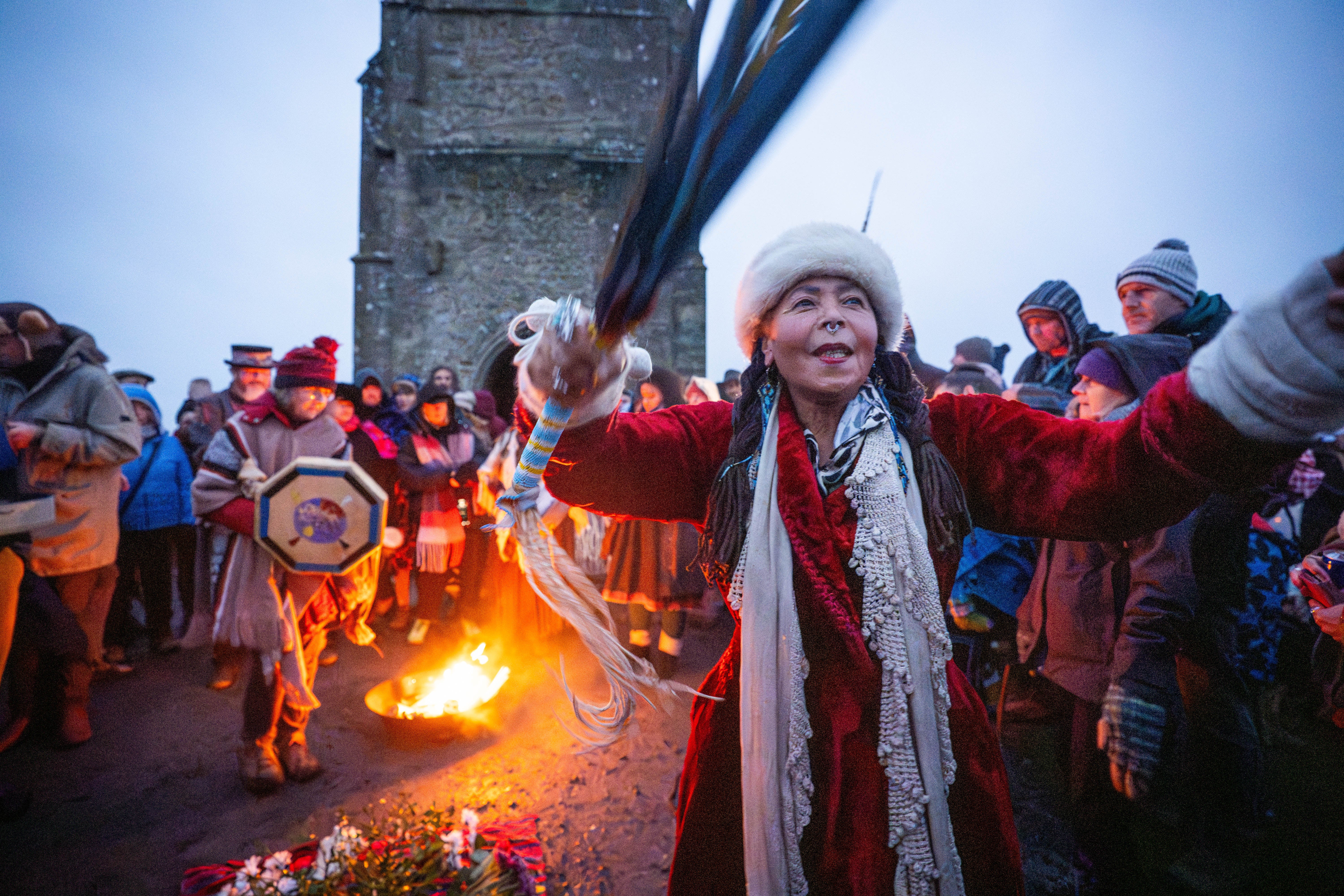 People take part in the winter solstice celebrations during sunrise at Glastonbury Tor in Somerset.