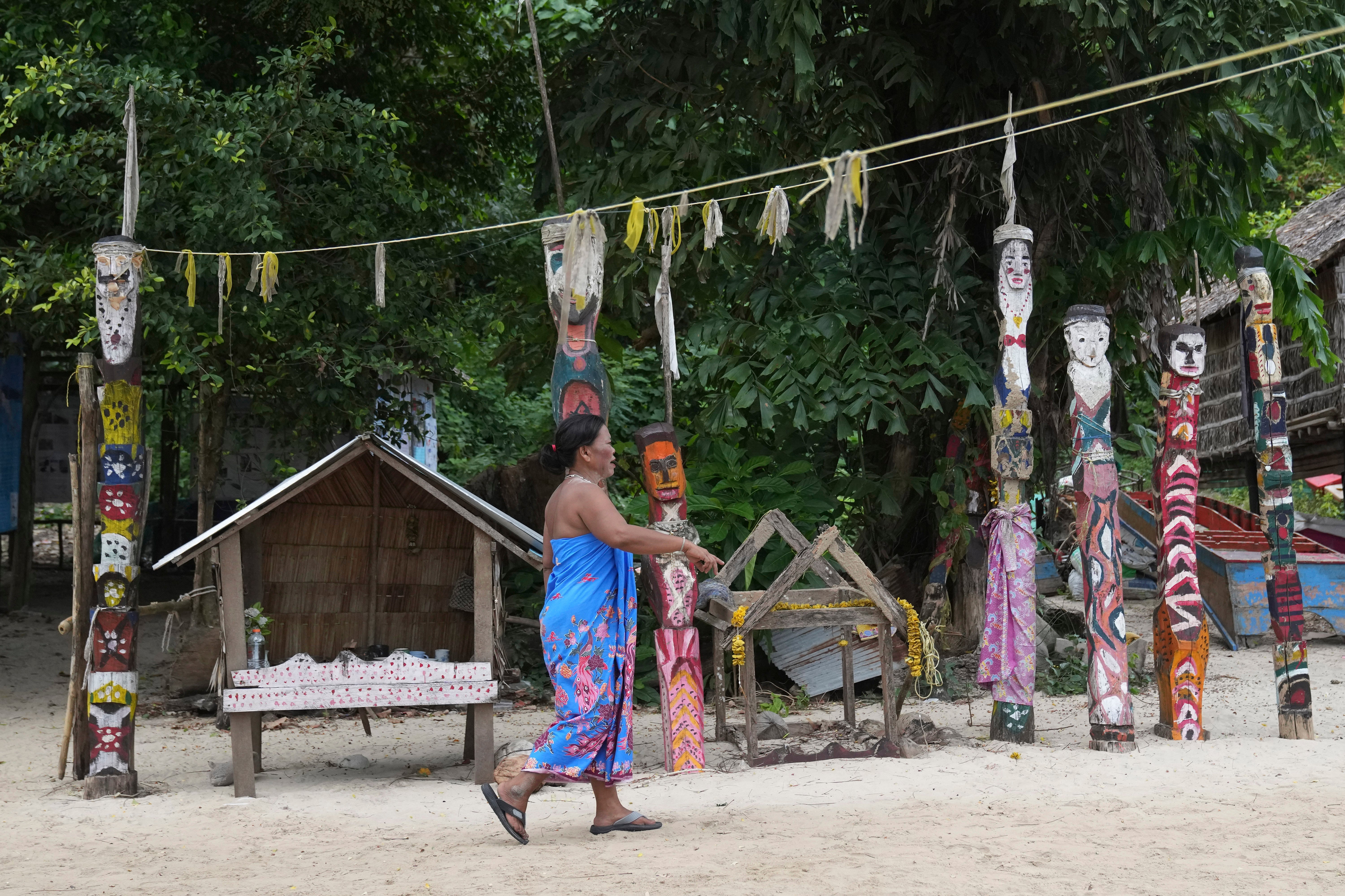 A Moken villager walks in front of spirit poles at Surin Islands