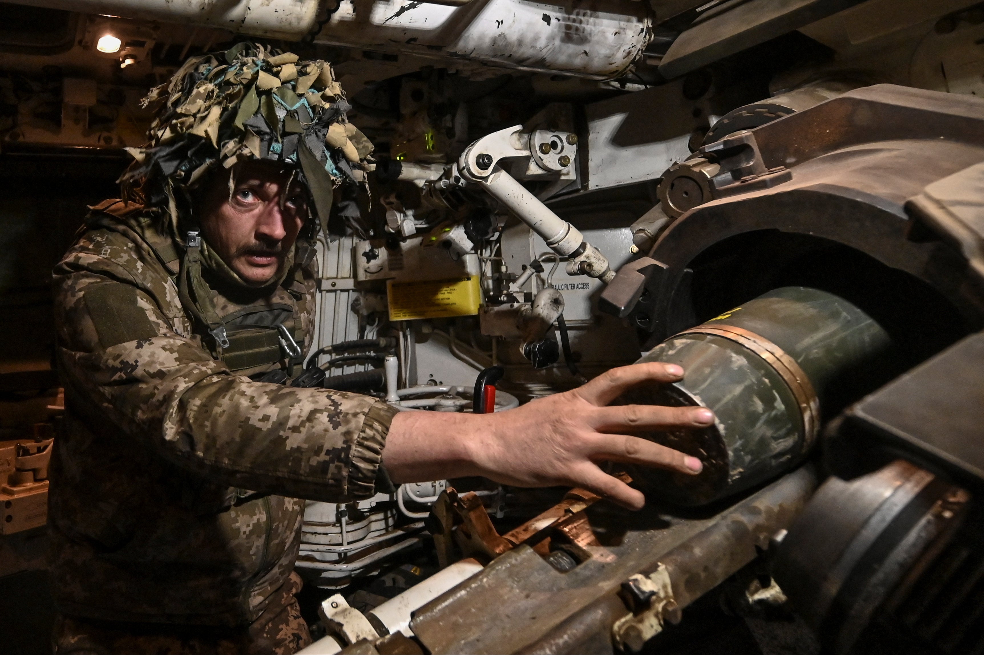 A Ukrainian serviceman of the 118th Separate Mechanised Brigade loads a shell into a barrel of a Paladin M109 self-propelled howitzer to be fired towards Russian troops