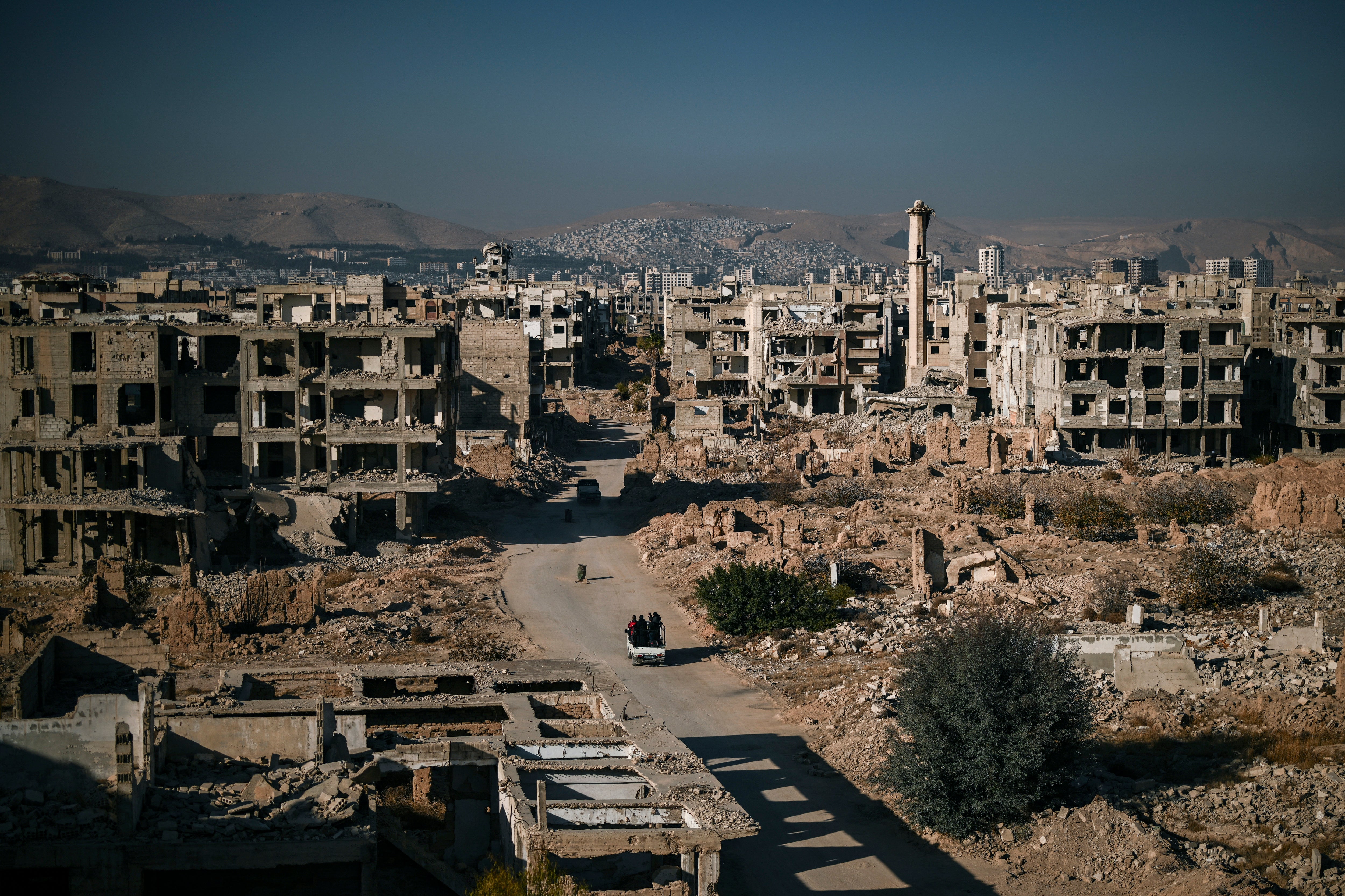 Cars drive on a road amid building destruction in the Syrian town of Jobar in Eastern Ghouta on the outskirts of Damascus