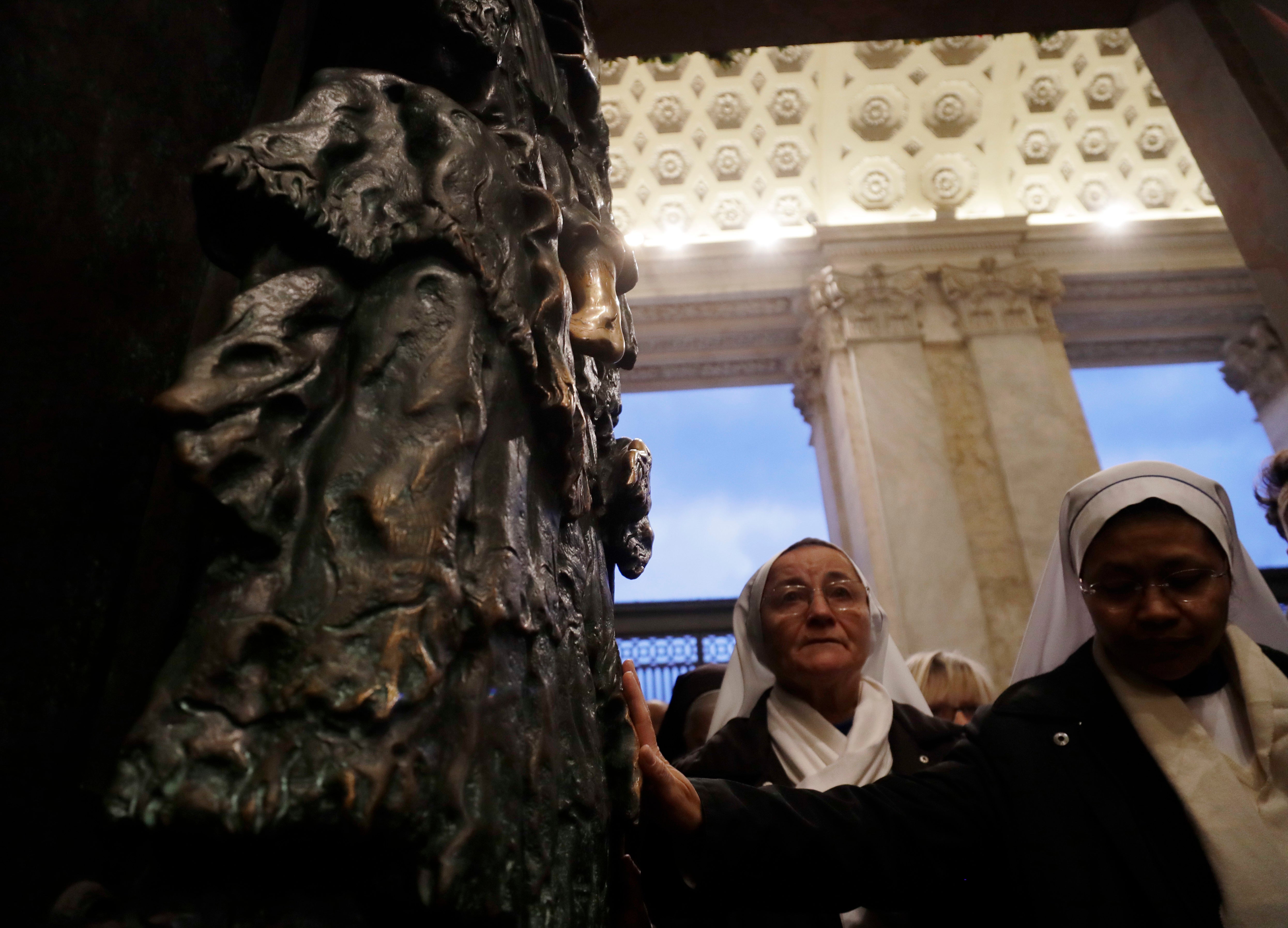 Nuns reach out to touch the the Holy Door of the St. John in Lateran basilica in Rome, Sunday