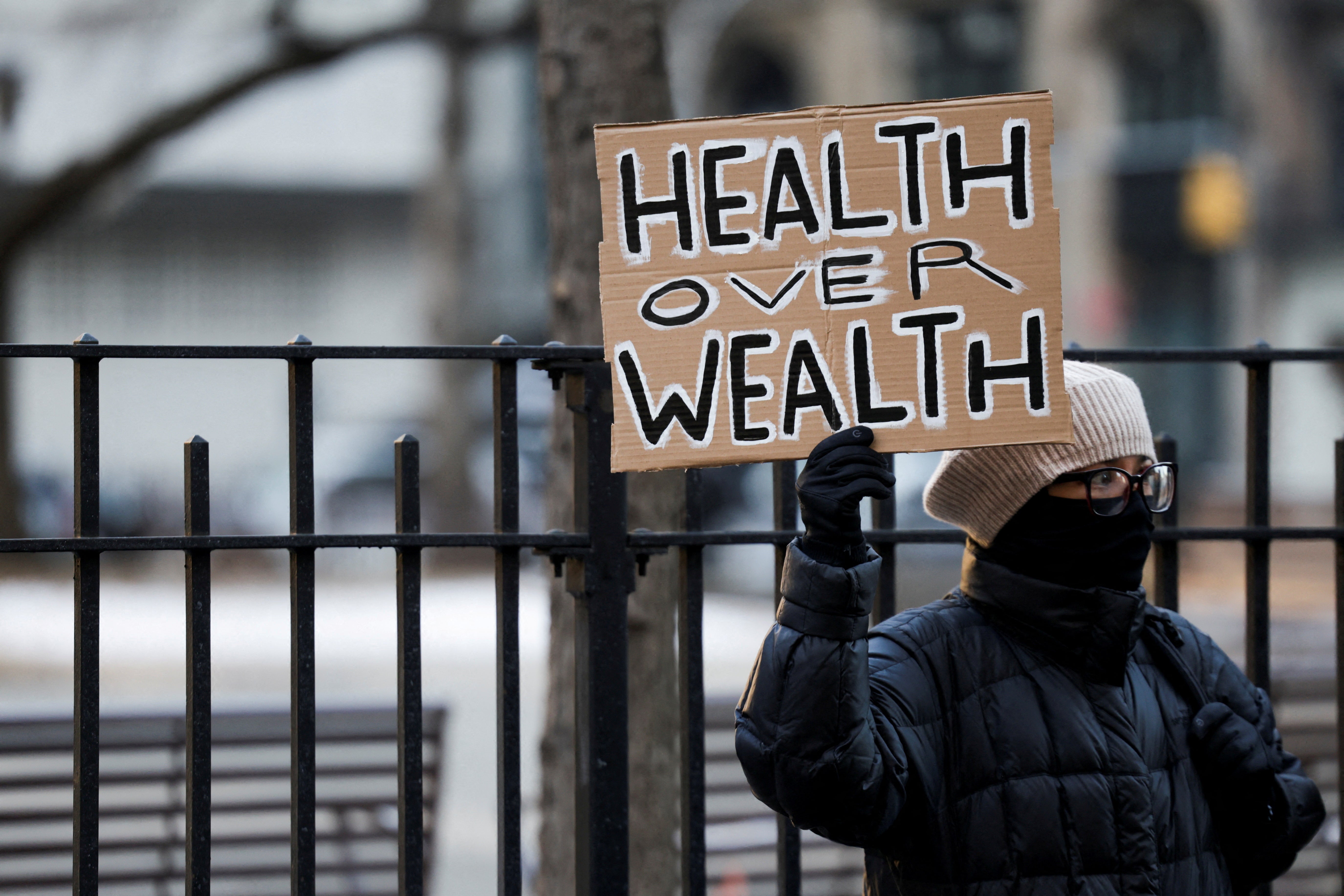 A demonstrator holds a sign that reads, “Health over wealth” outside of Mangione’s Manhattan arraignment Monday morning