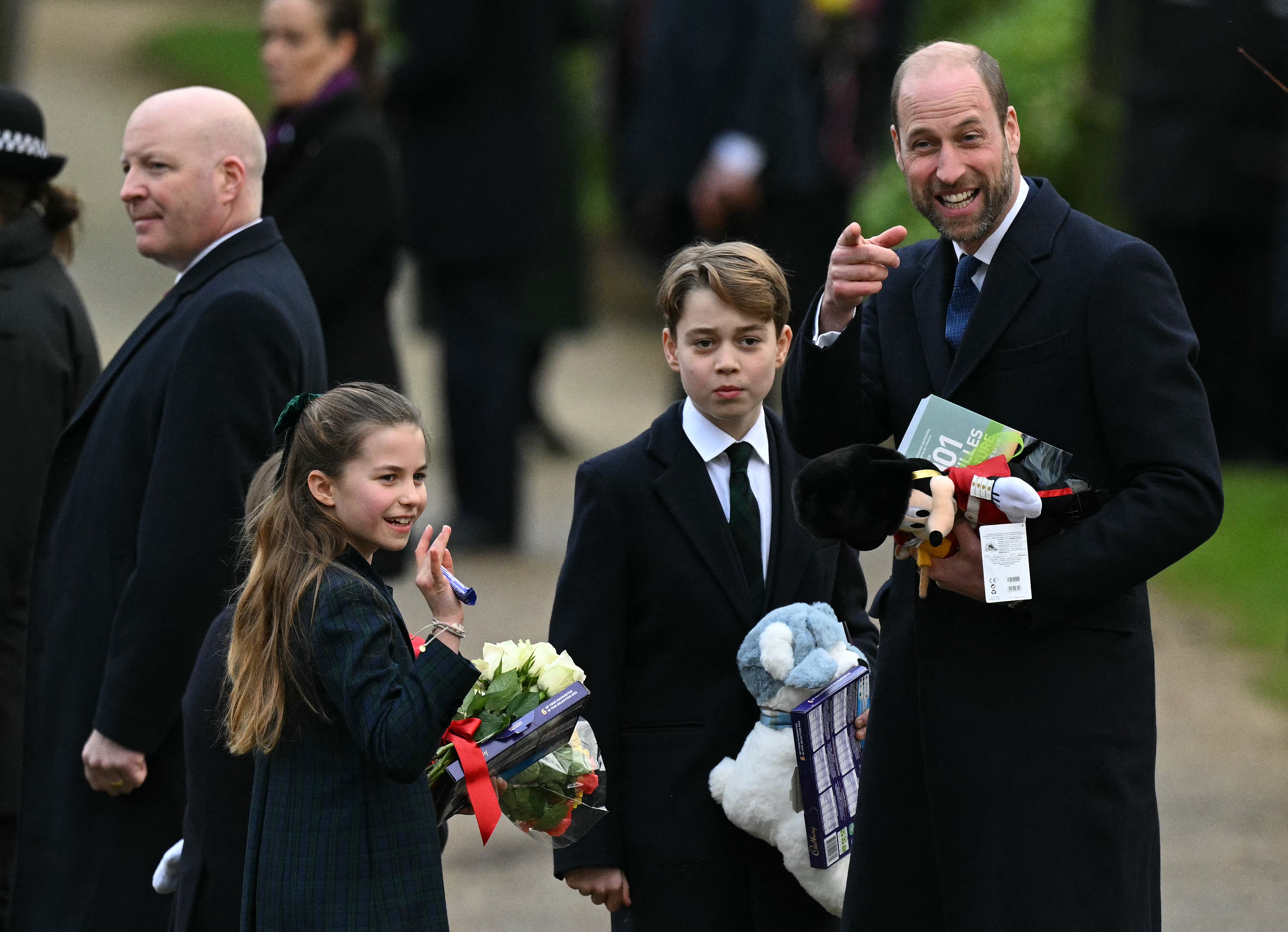 Prince William and his children are pictured outside church on Christmas morning, clutching gifts from well-wishers