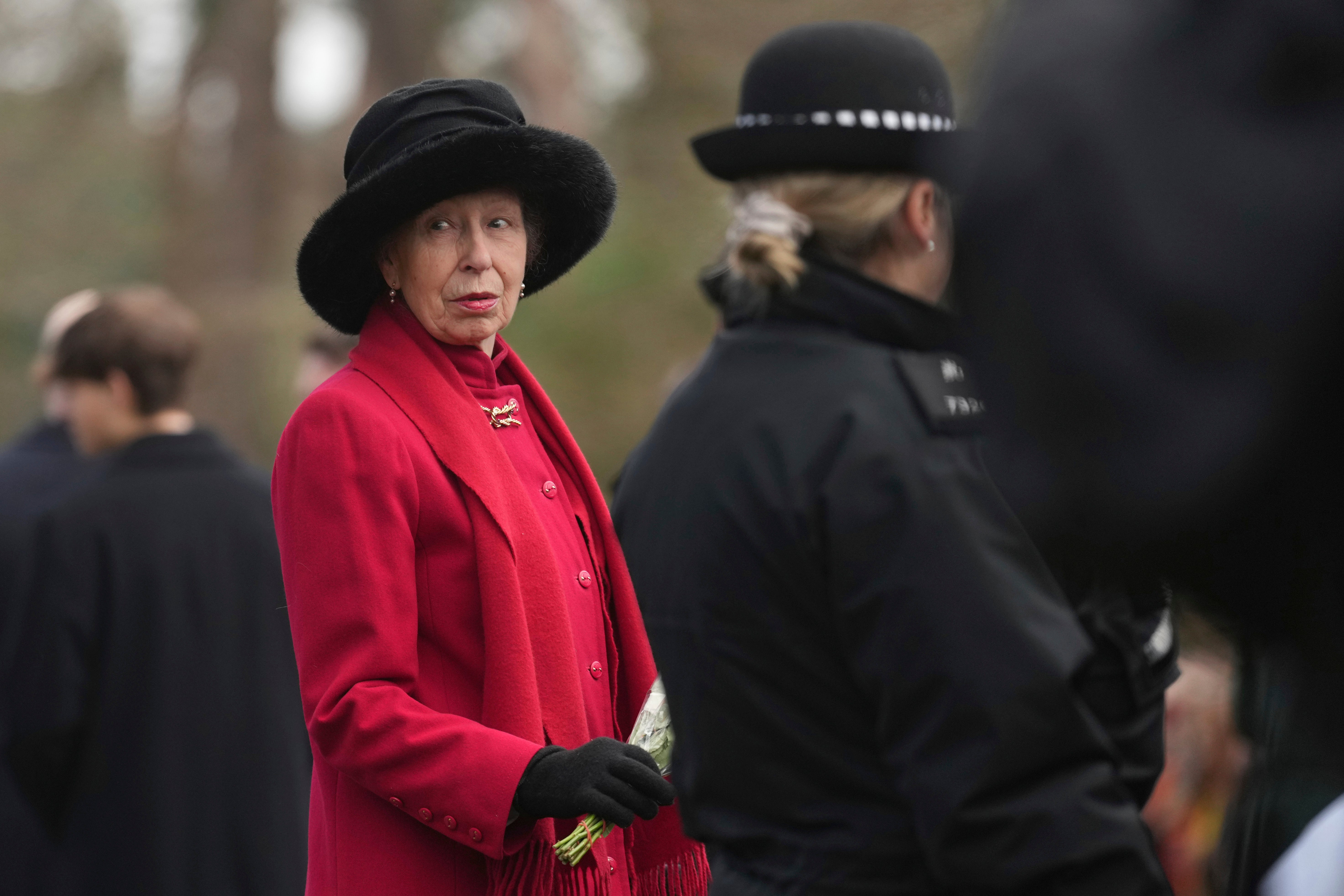 Princess Anne looks round as she hold a bouquet of flowers after attending the Christmas day service