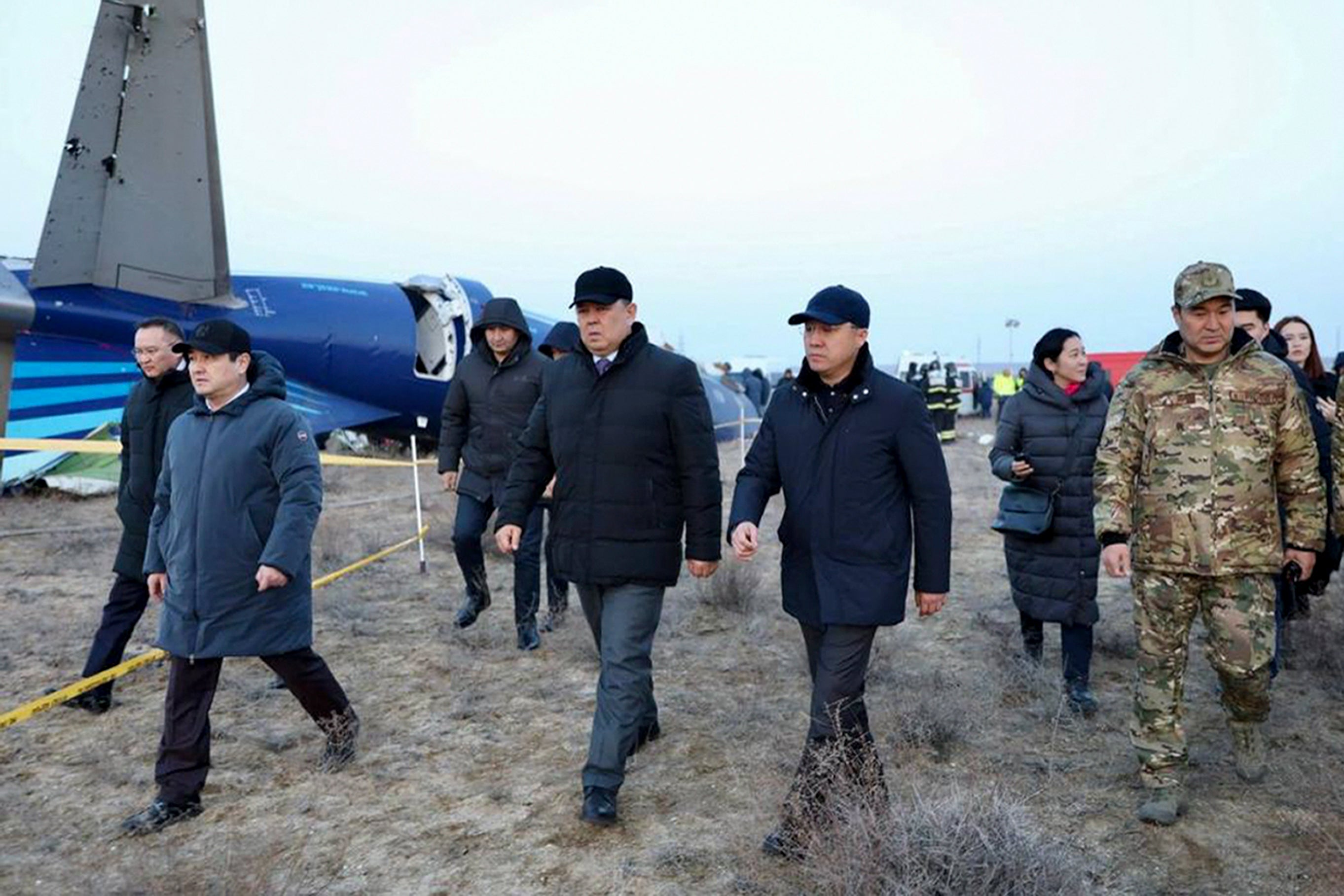 Members of an investigation committee and local officials walk past the wreckage of the Azerbaijan Airlines Embraer 190